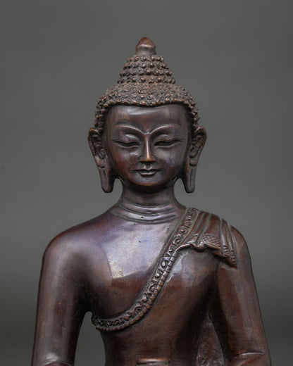 Close-up of Amitabha Buddha copper statue showing serene face, curled hair and carved shoulder drape