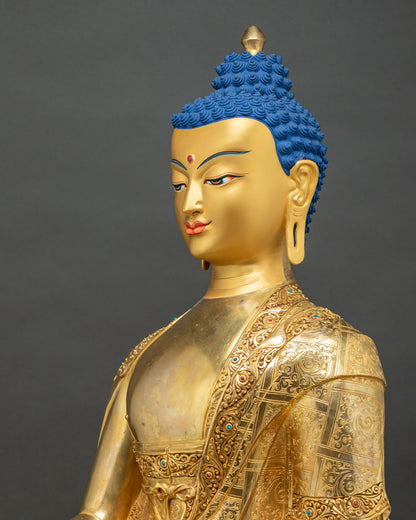 Angled view of gold Shakyamuni Buddha statue showing serene face and robe