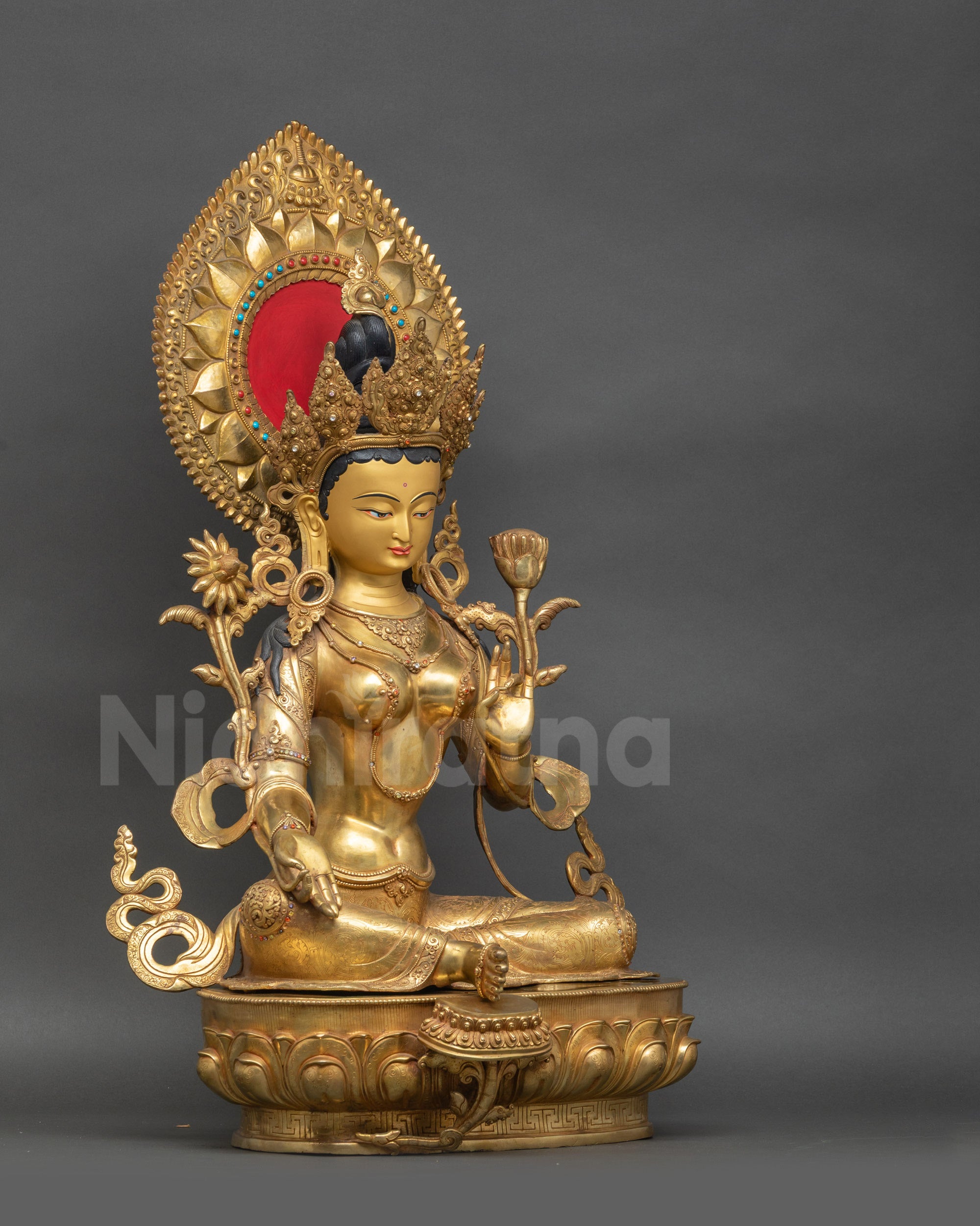 Angled view of Green Tara statue holding Utpala flower on lotus throne