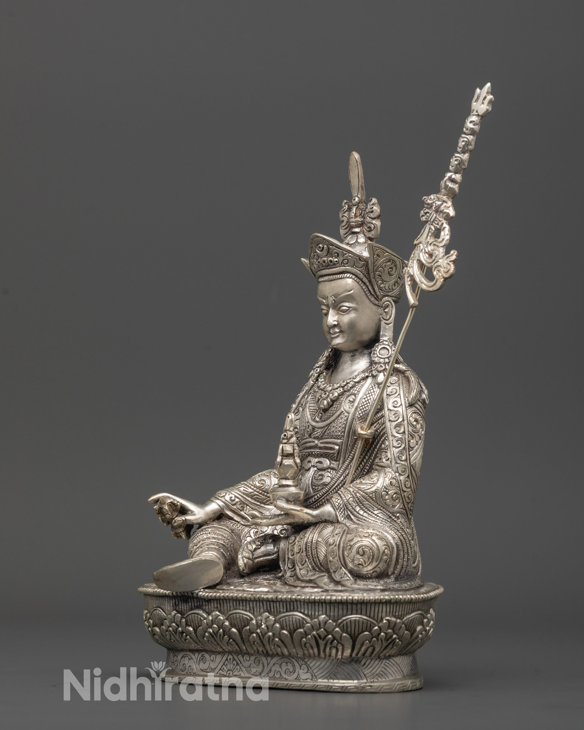 Angled view of handcrafted silver-plated Guru Rinpoche statue showcasing intricate lotus