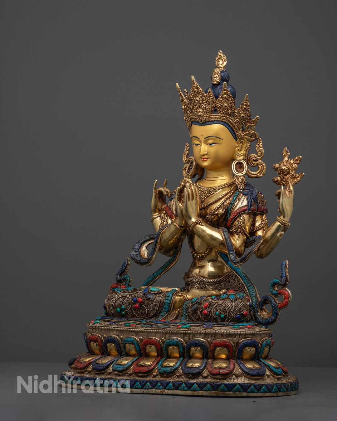 Artisan handcrafting a Chenrezig statue in Nepal using the traditional lost wax technique with detailed stone and gold adornments.