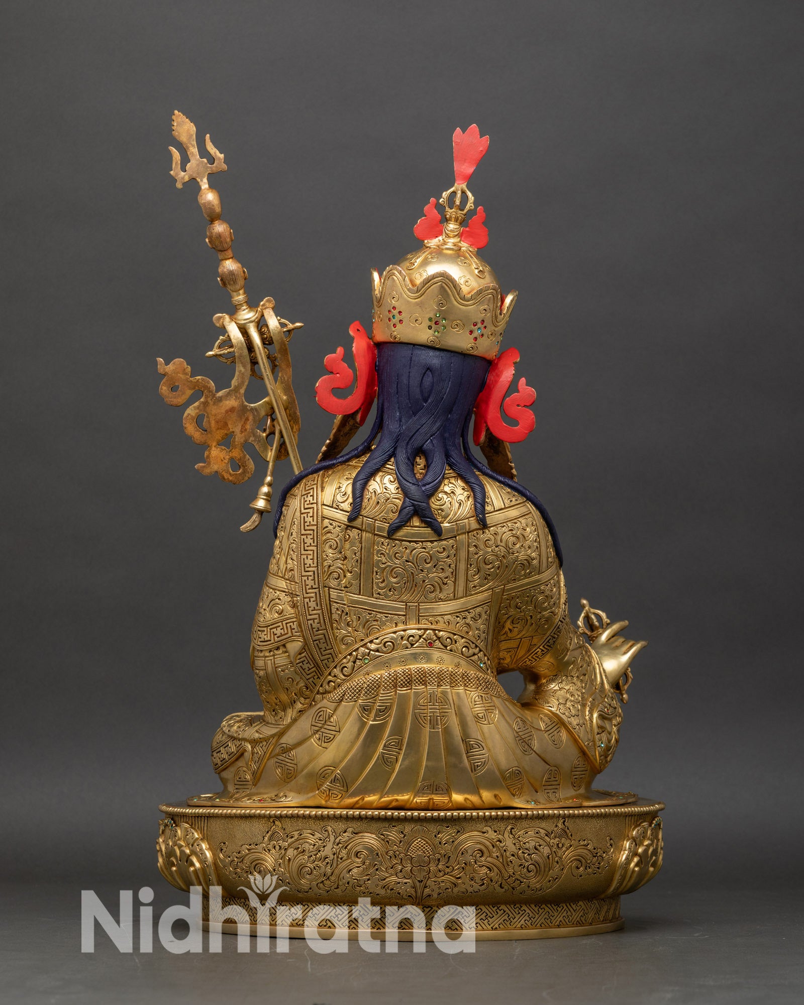 Back view of Guru Rinpoche statue showing lotus pedestal, robes, and flowing banner
