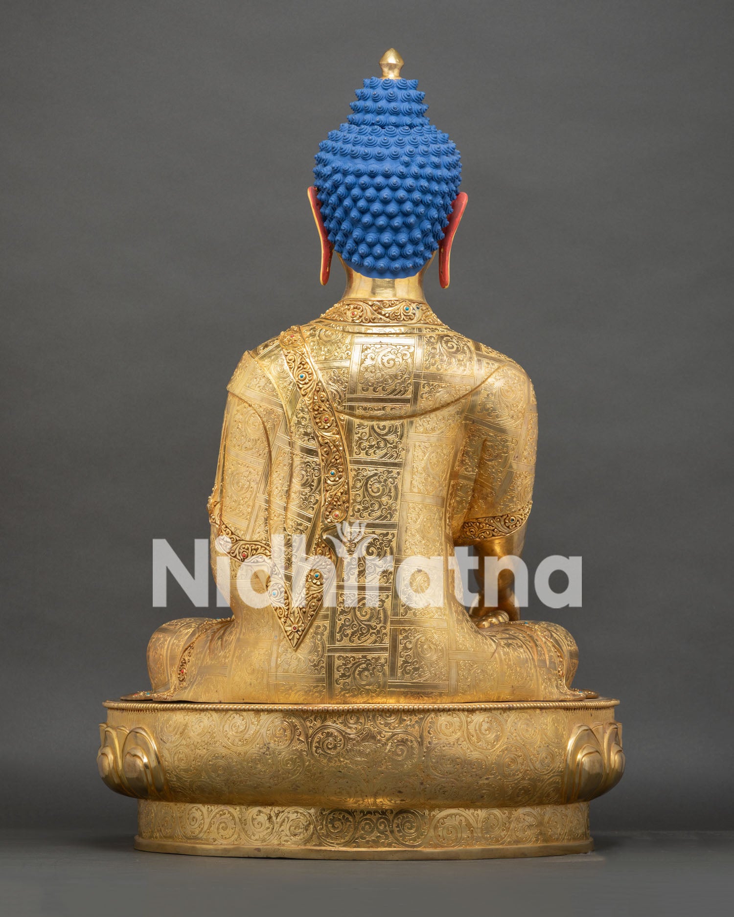 Back view of gold gilded Shakyamuni Buddha statue showing blue hair and robe drape