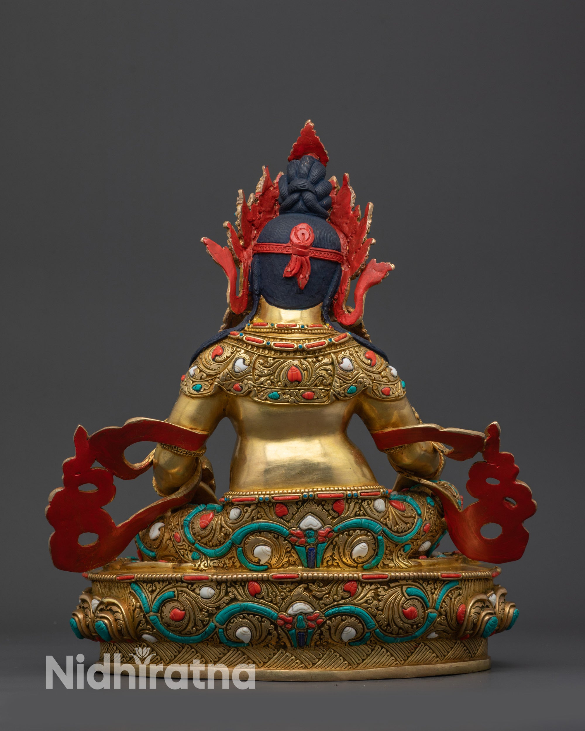 Back view Dzambhala Statue displaying detailed carvings, warm shine, and radiant glow
