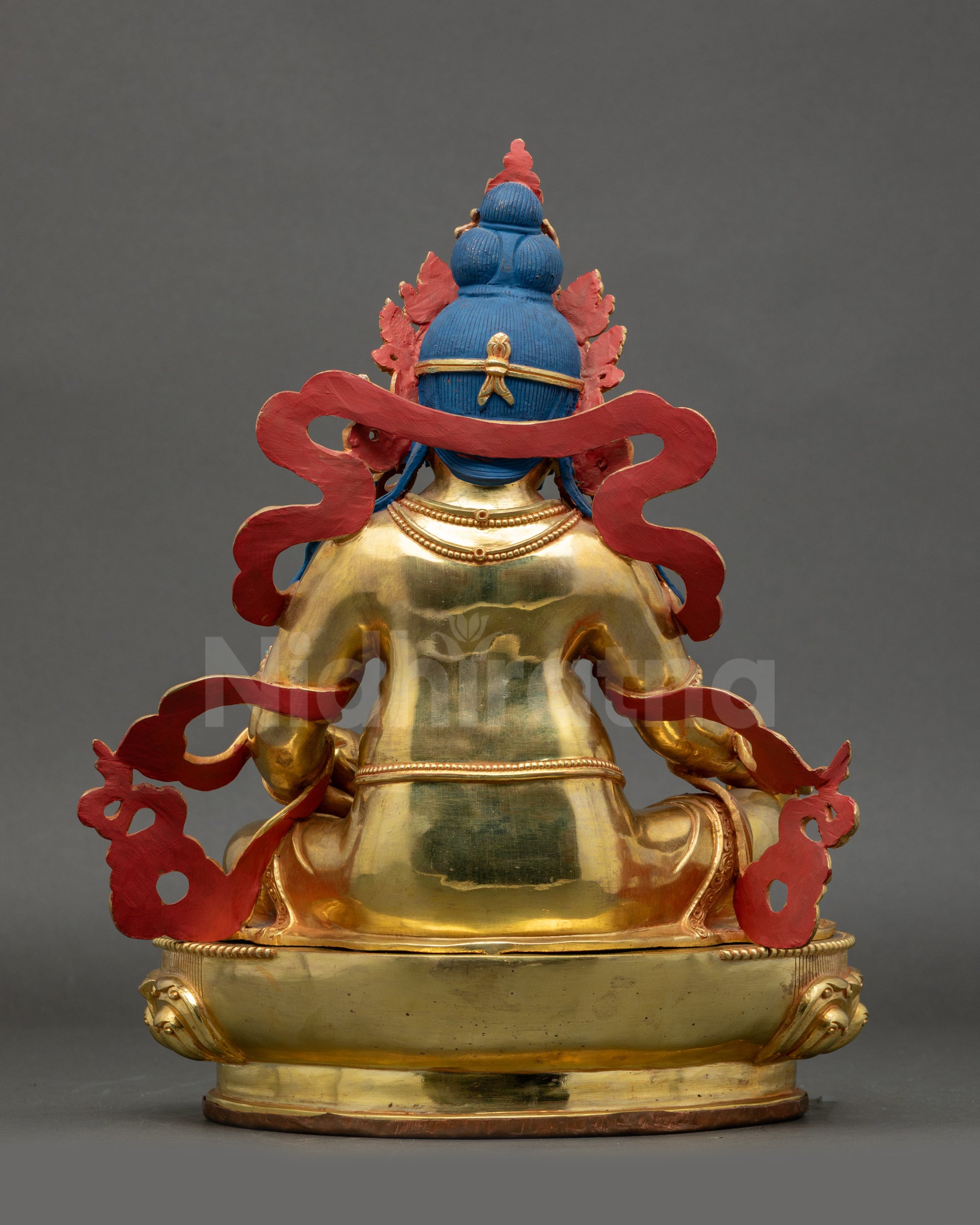 Back view Dzambhala statue showing intricate patterns on garments and lotus seat