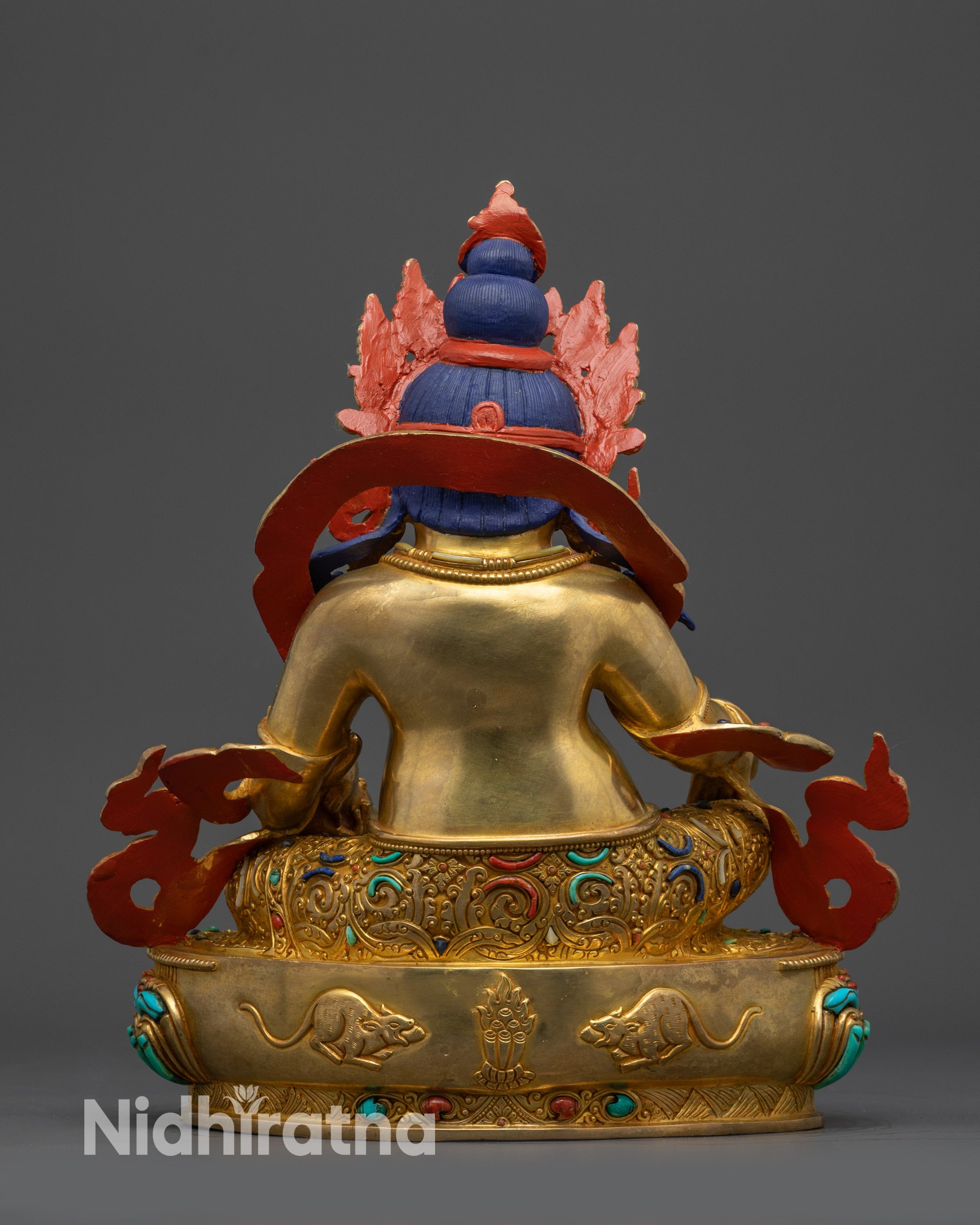 Back view Dzambhala with elaborate carved garments radiant gold-gilded finish and warm glowing details on the lotus pedestal