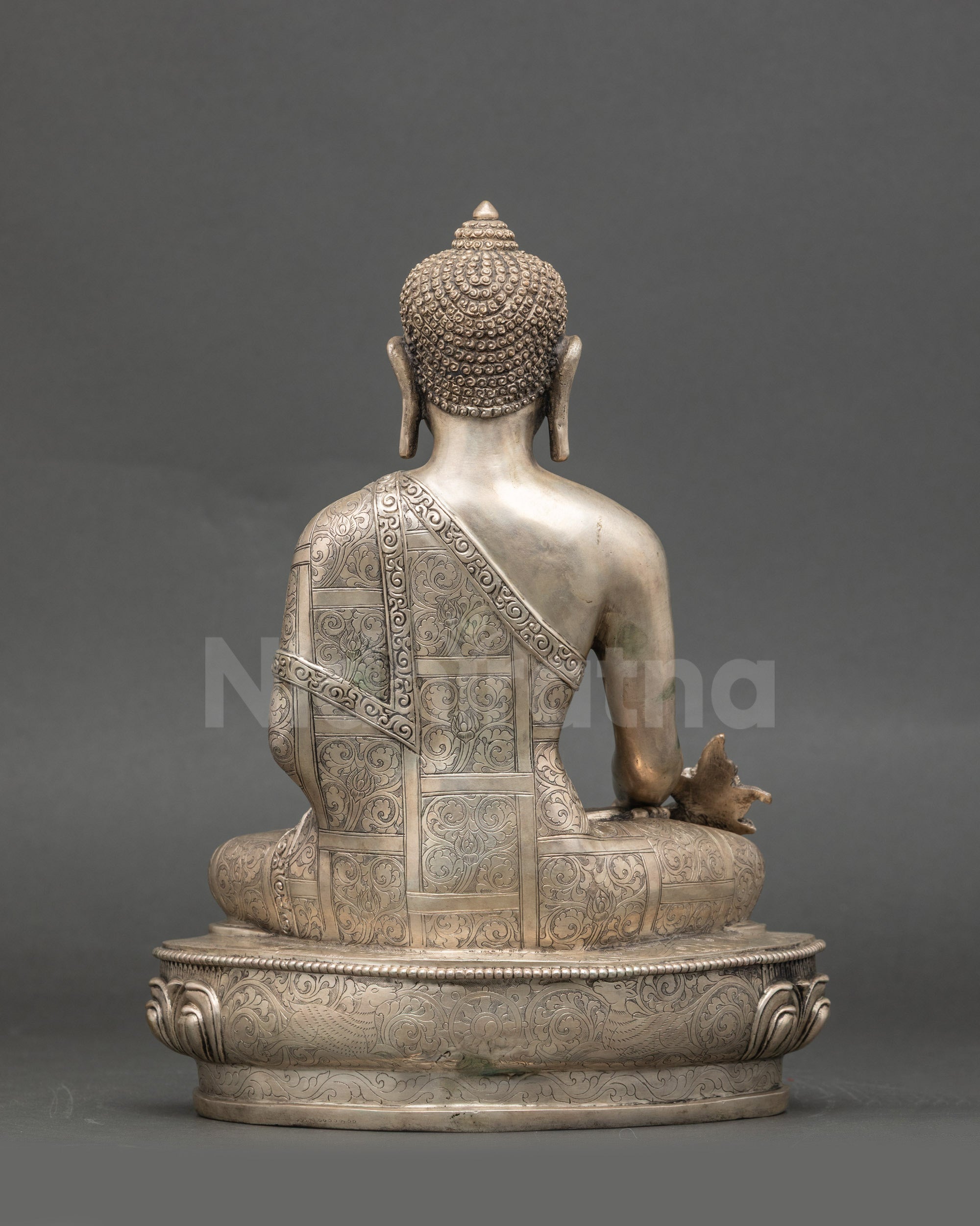 Back view of the Medicine Buddha statue seated, intricate silver-plated Nepalese craftsmanship