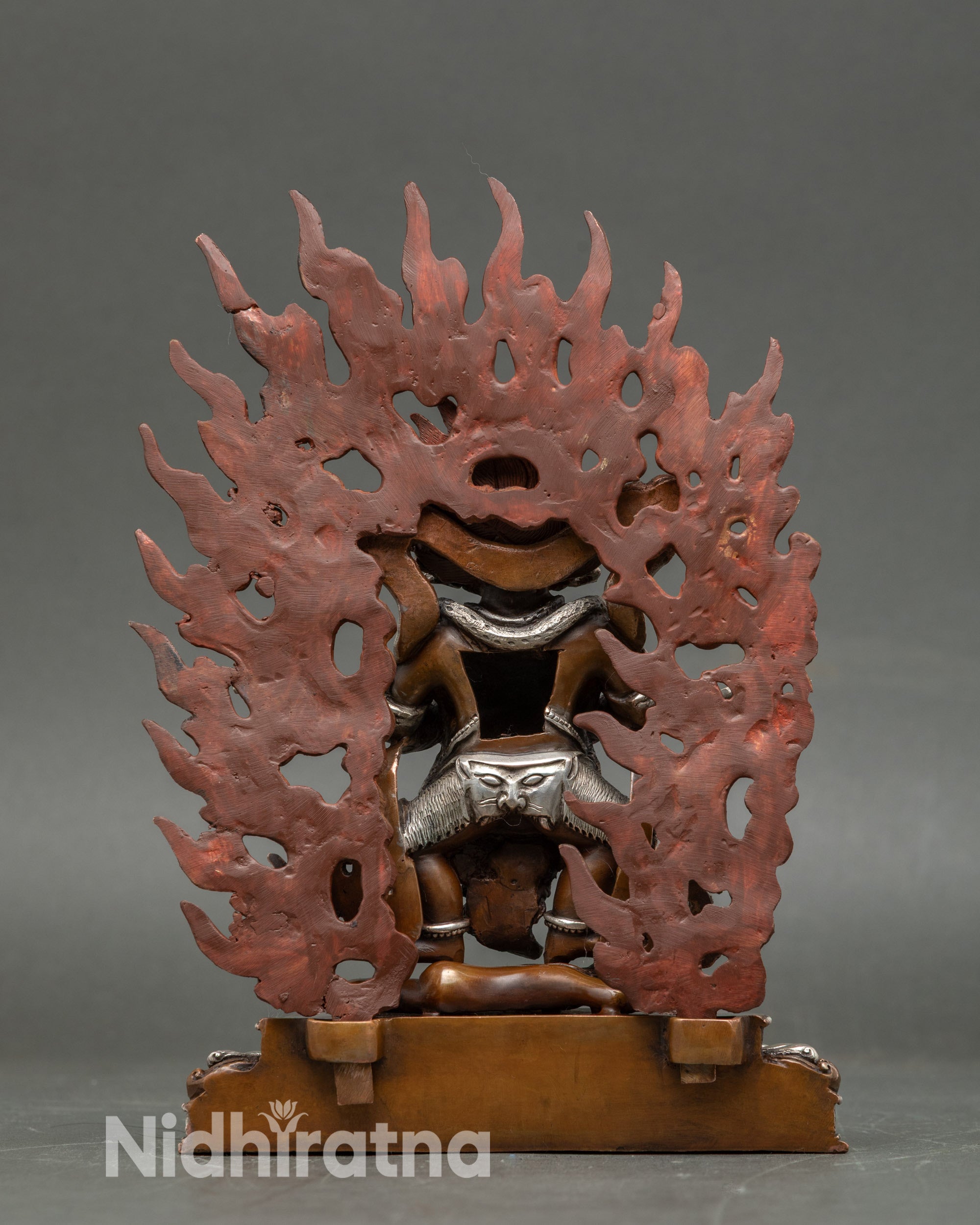 Back view Sakya Mahakala sculpture showing flowing robes, intricate ornaments, and fire flames