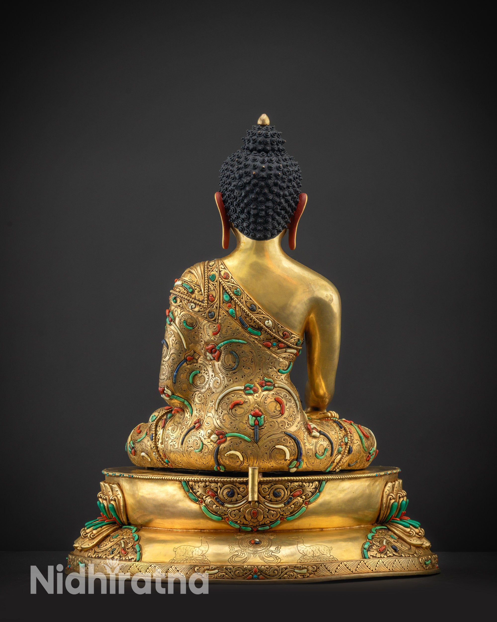 Back view Shakyamuni Buddha statue without halo highlighting robe texture and carvings

