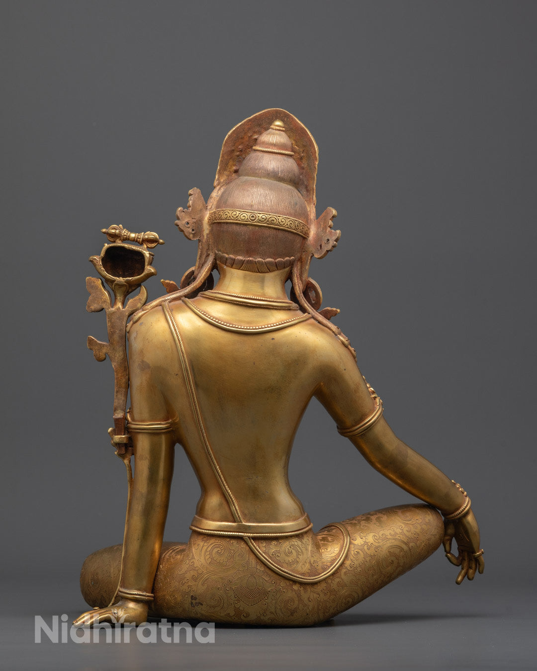 Back view highlighting the finely carved lower garment and rich detailing on statue