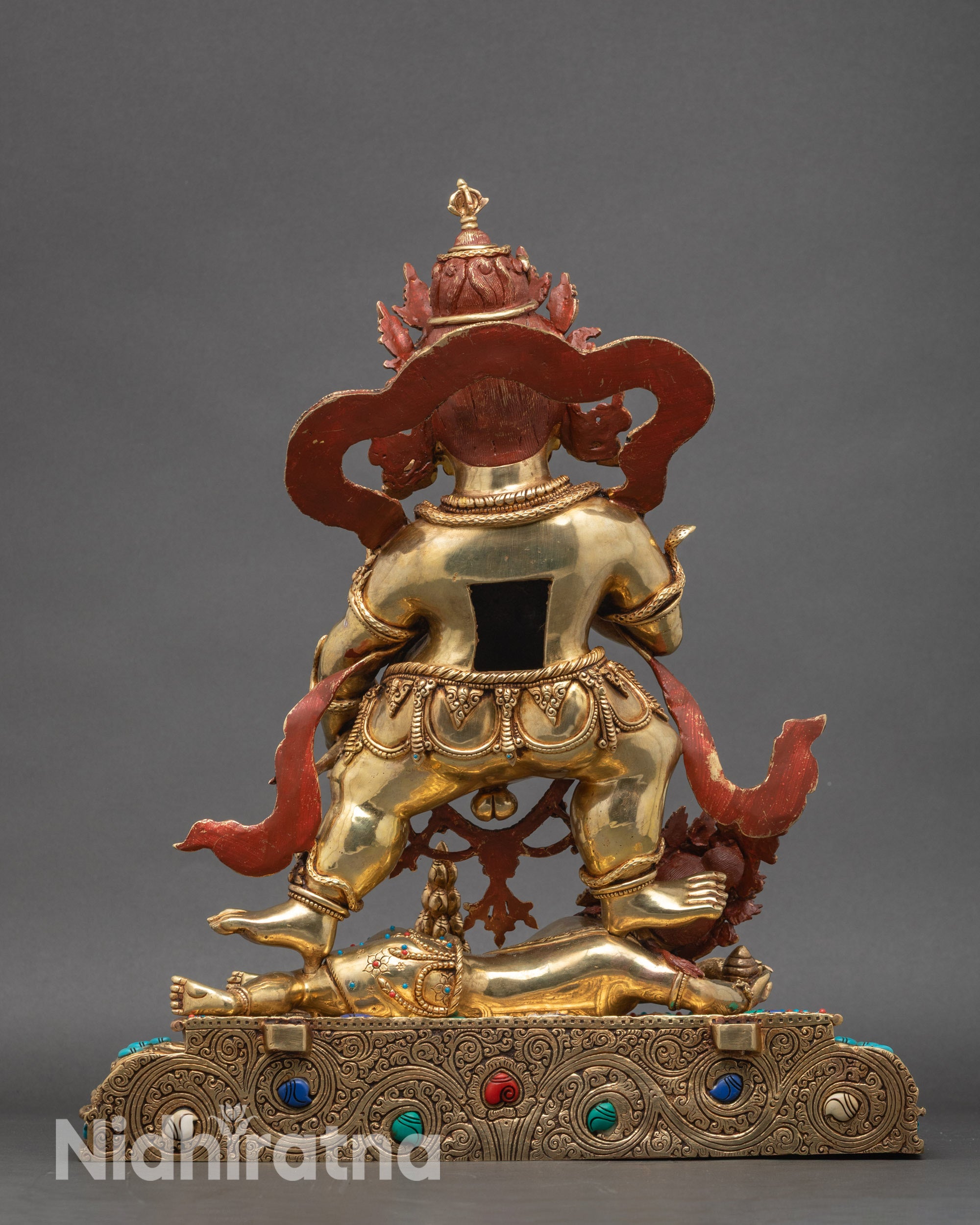 Back view of Black Dzambhala statue showing draped tiger skin, lotus throne, and ornate patterns