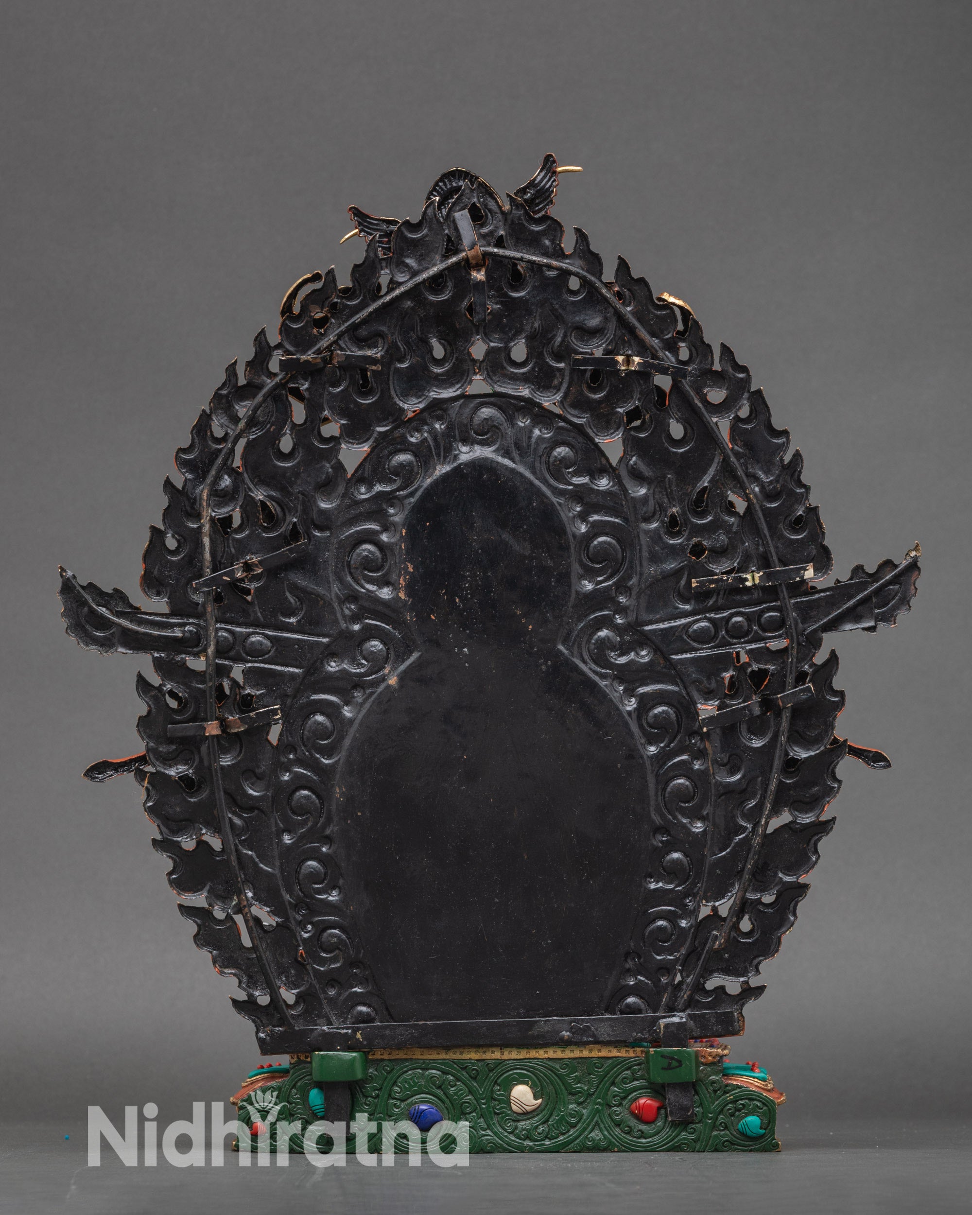 Back view of Black Dzambhala statue showing lotus throne and flame halo engraving