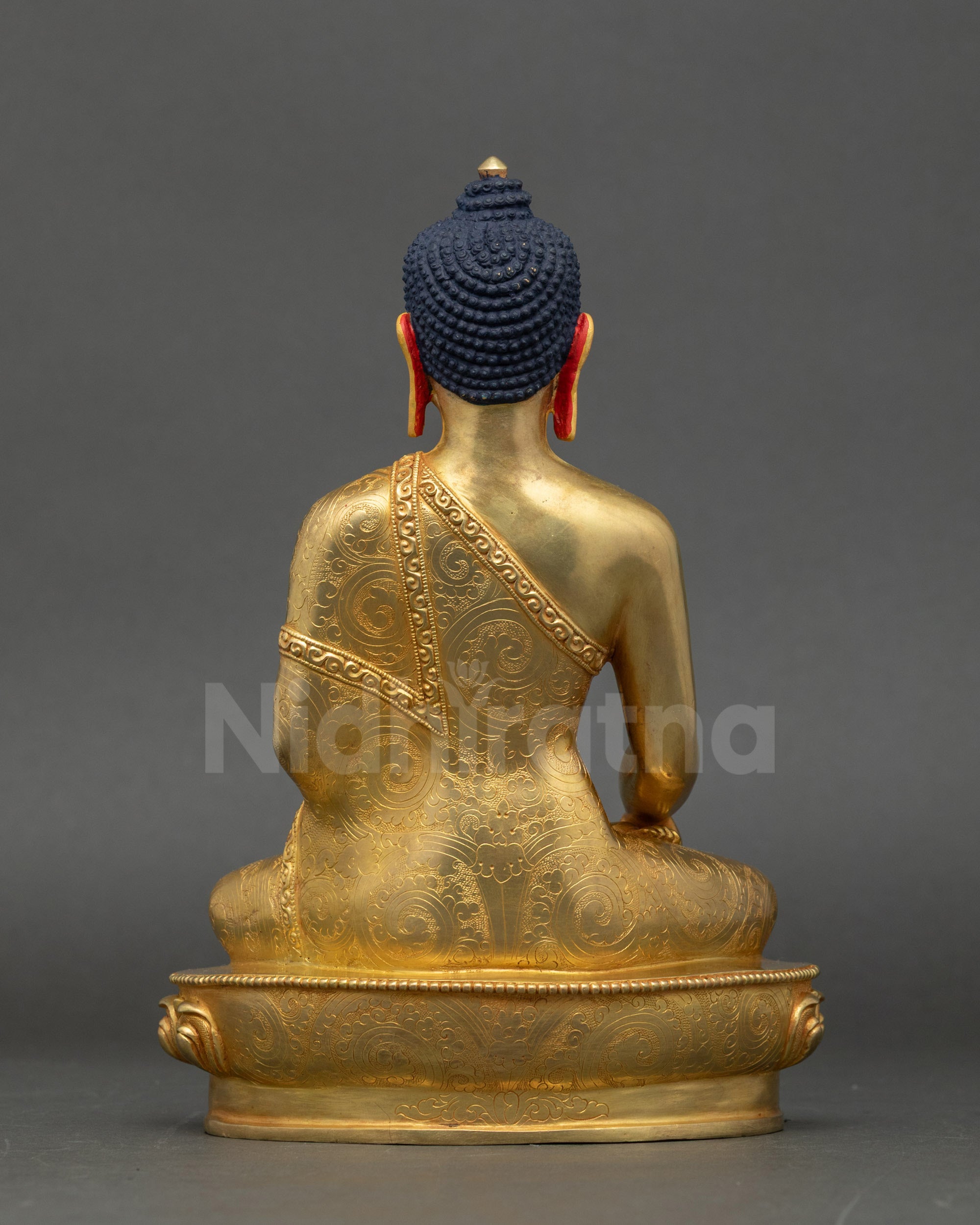 Back view of Buddha Shakyamuni sculpture highlighting patterned robe and lotus base