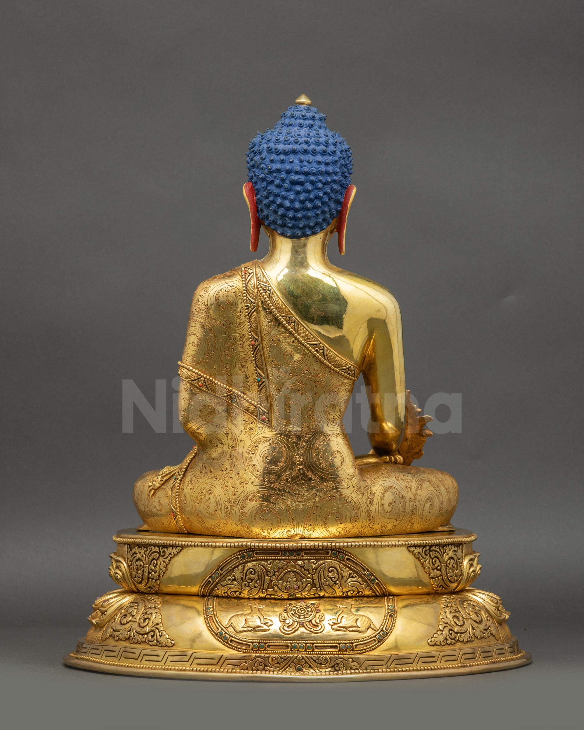 Back view of Buddha statue featuring Wisdom Wheel and pair of Deer on pedestal