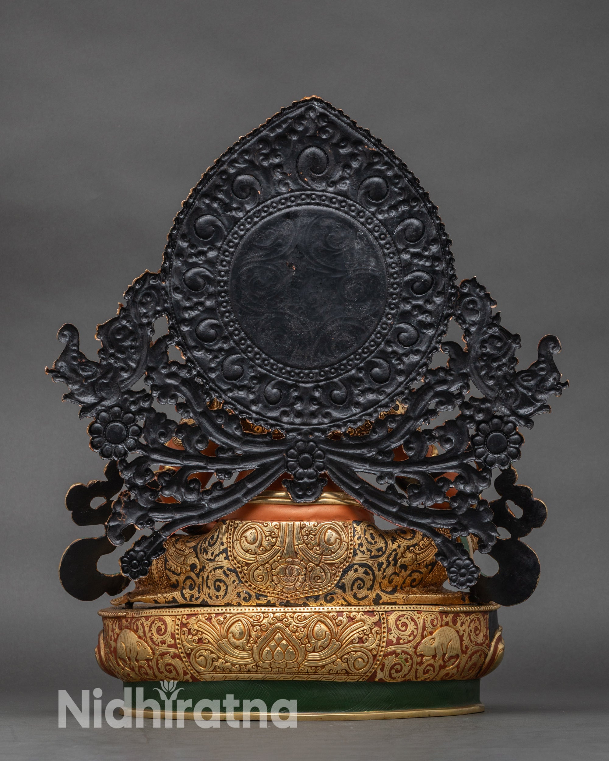 Back view of Dzambhala statue with detailed halo and lotus pedestal engraving
