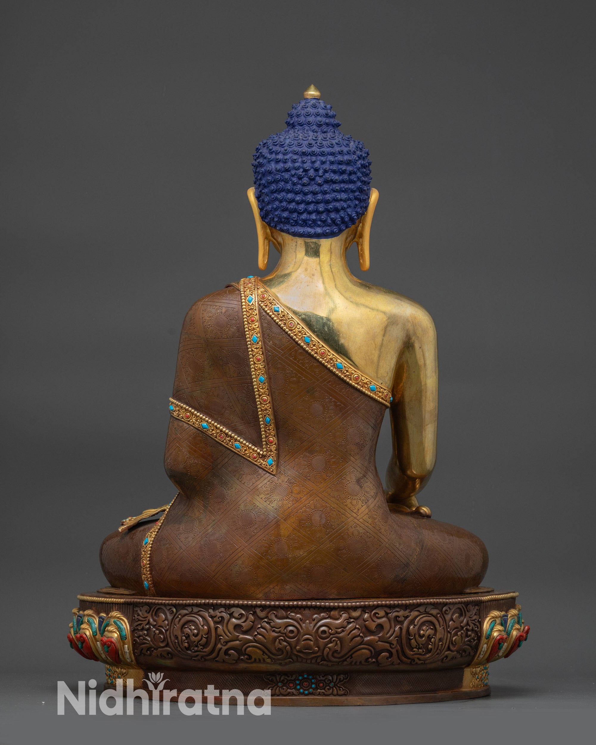 Back view of Gautama Buddha Statue displaying carved garments and gold-gilded base