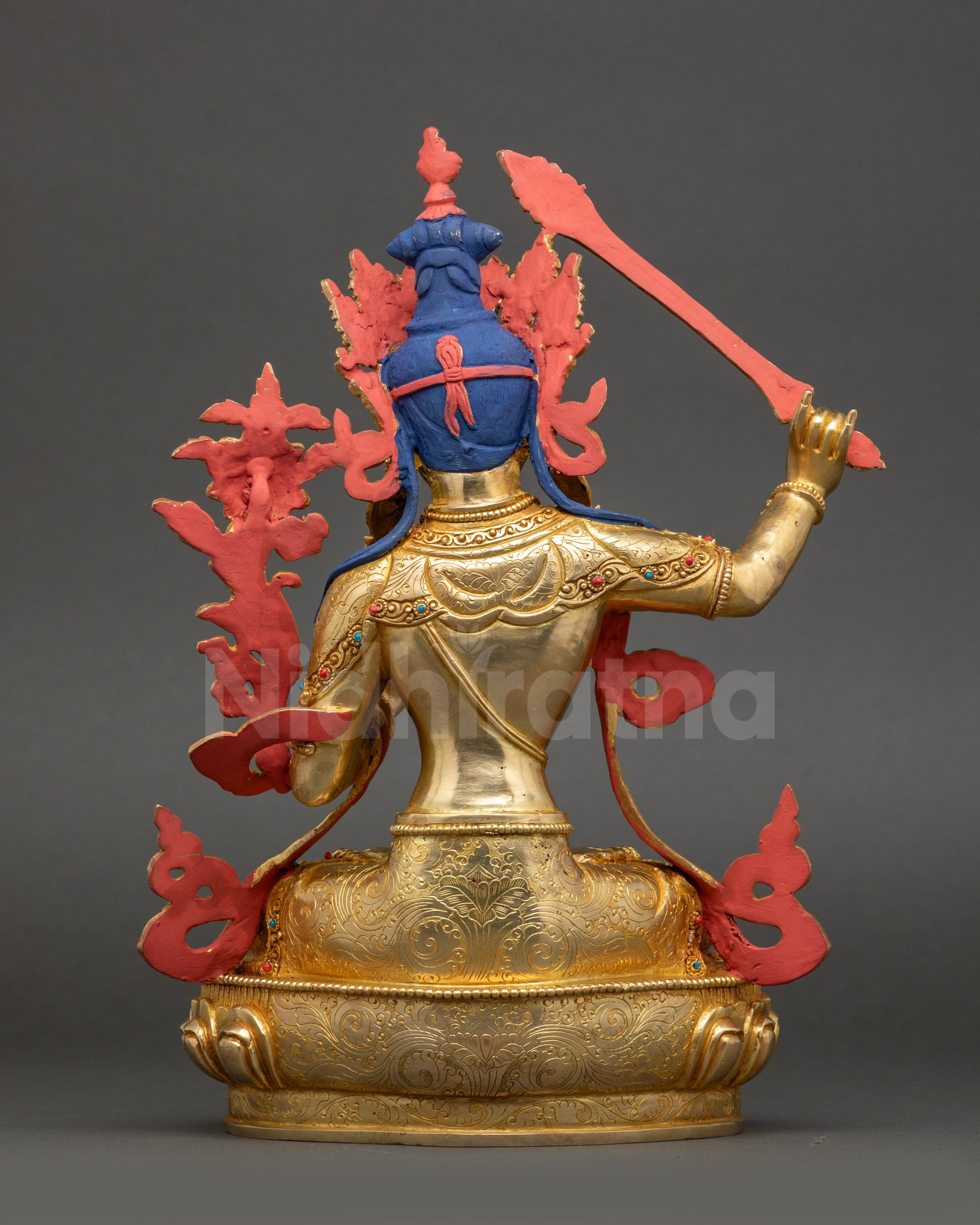 Back view of Manjushri statue showing carved robe patterns and lotus base