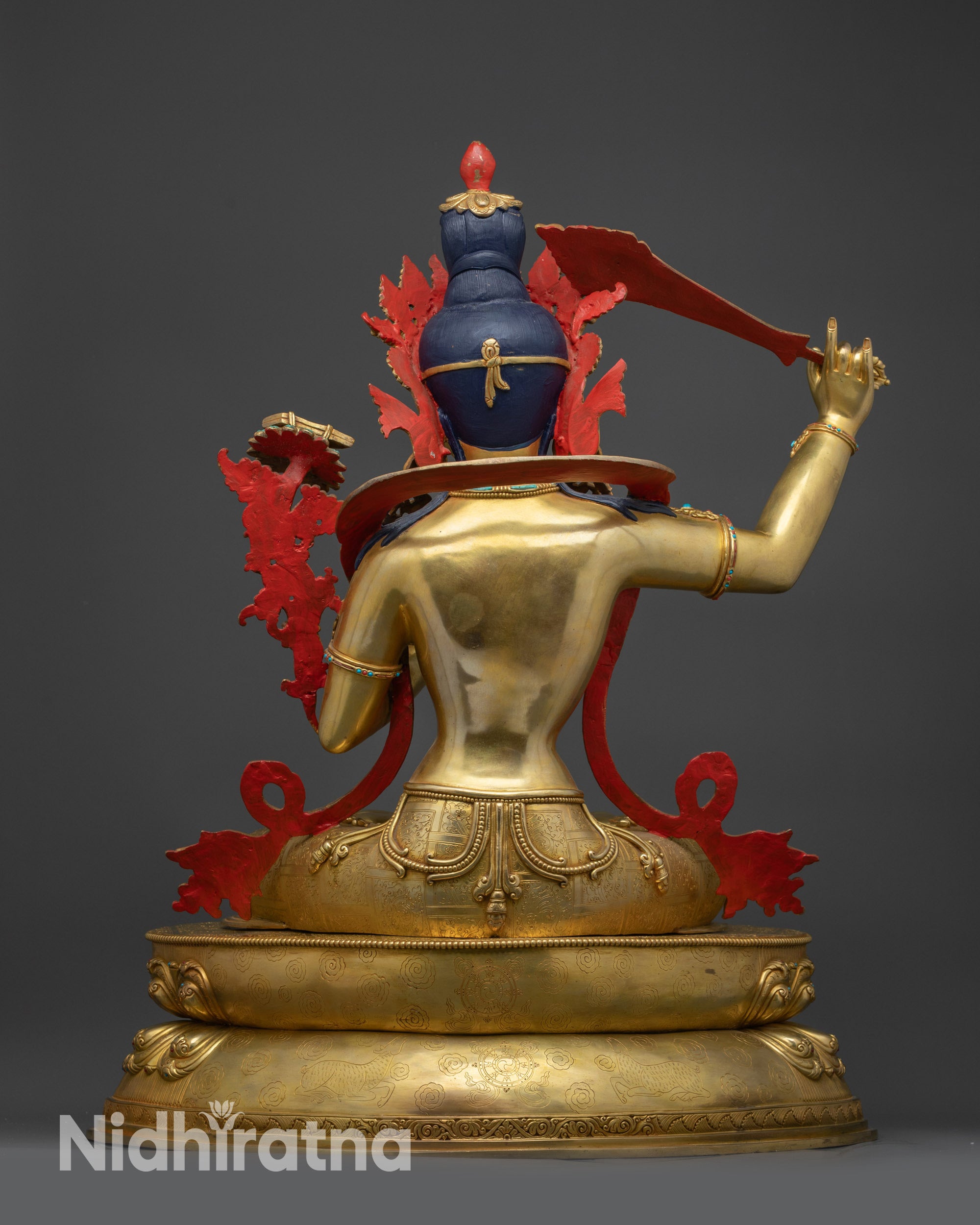 Back view of Manjushri statue showing lotus base with dharma wheel and deer