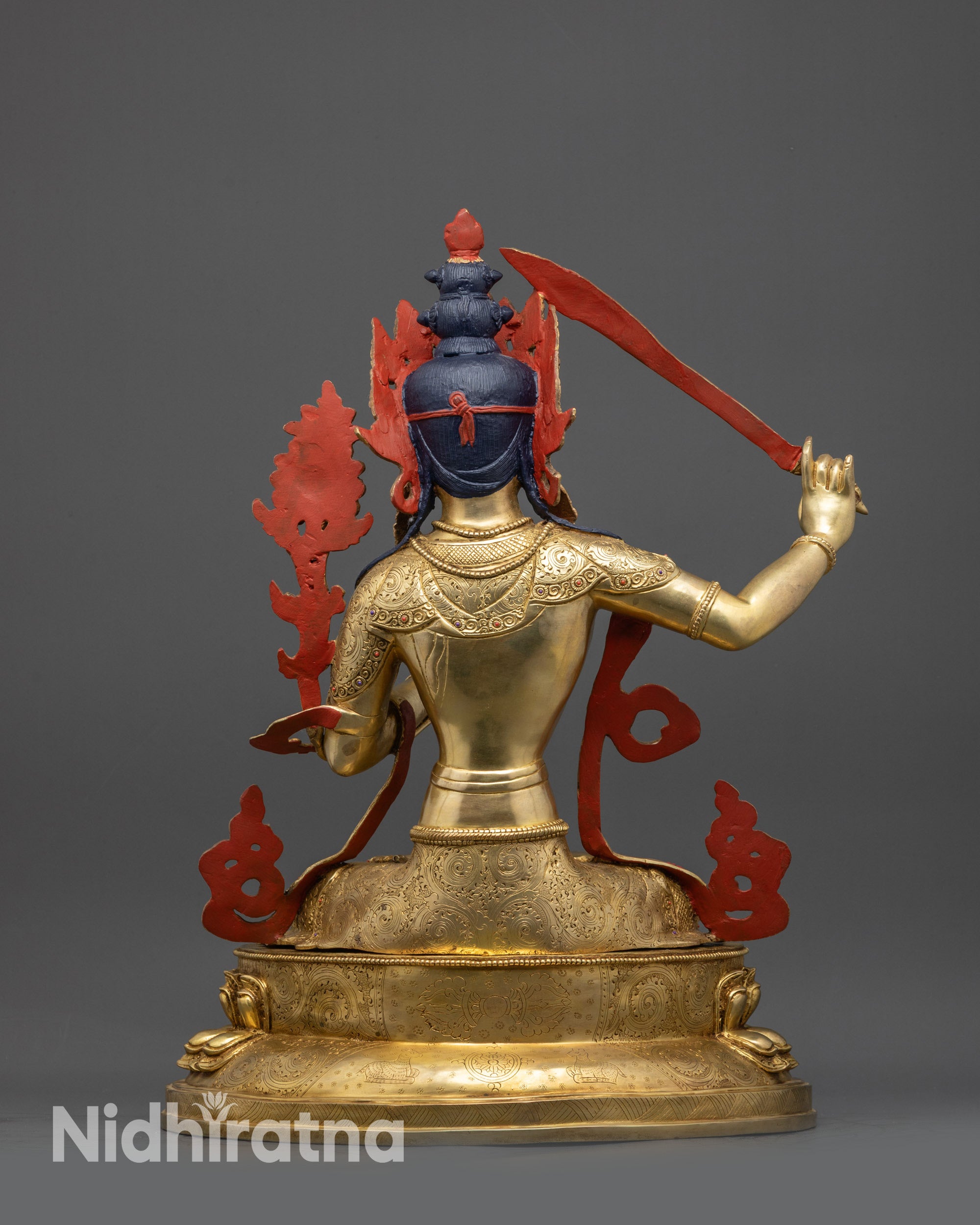 Back view of Manjushri statue showing lotus pedestal with vajra, Dharma wheel, and deer