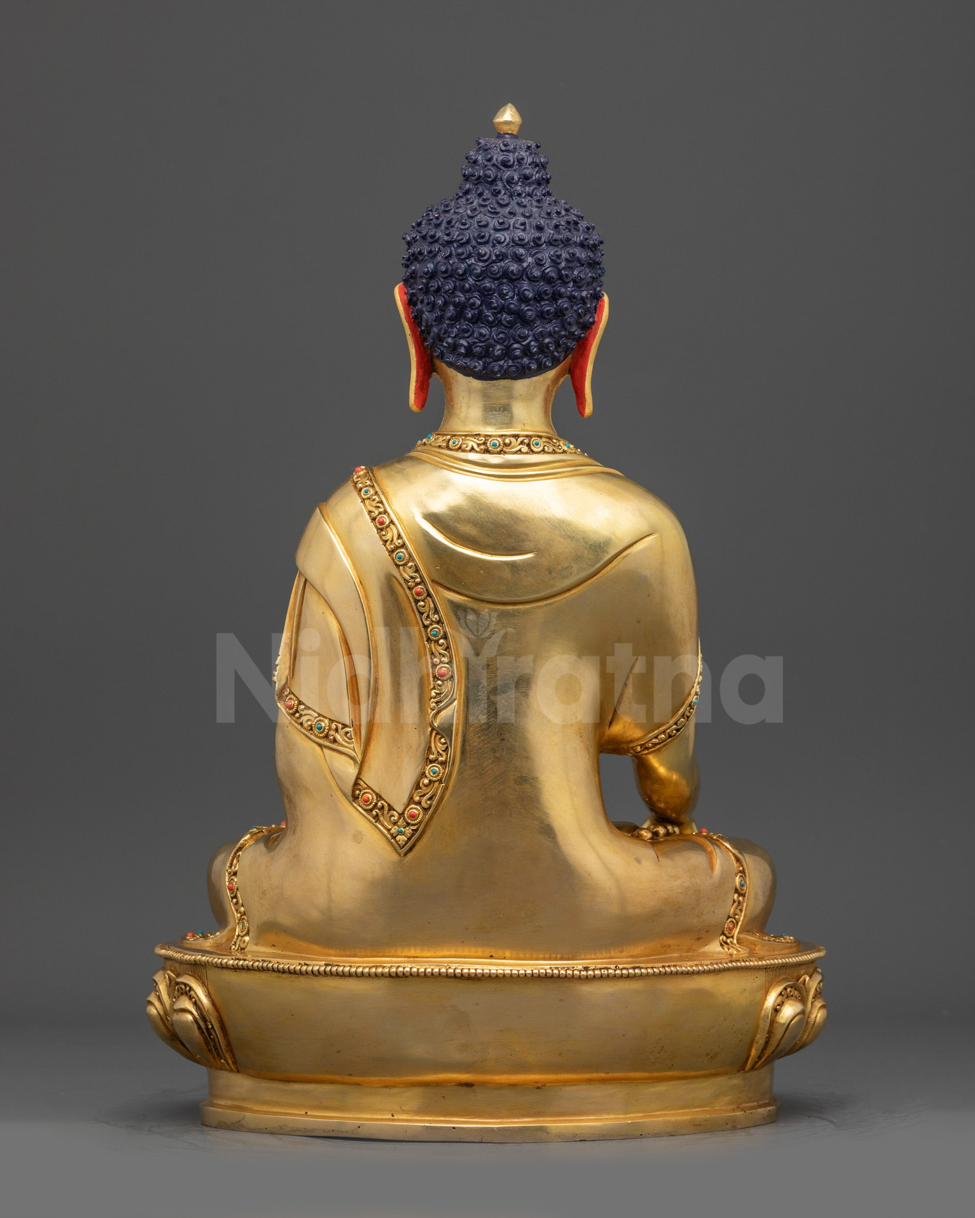Back view of Shaka Buddha statue with carved robes and gold fire-gilded lotus base