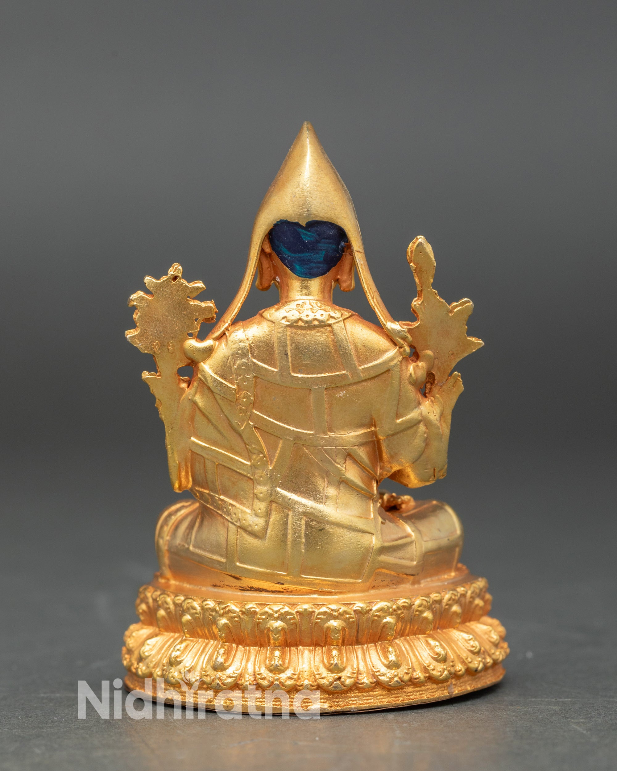 Back view of Shakya Pandit statue on altar, showcasing detailed robes and sacred posture