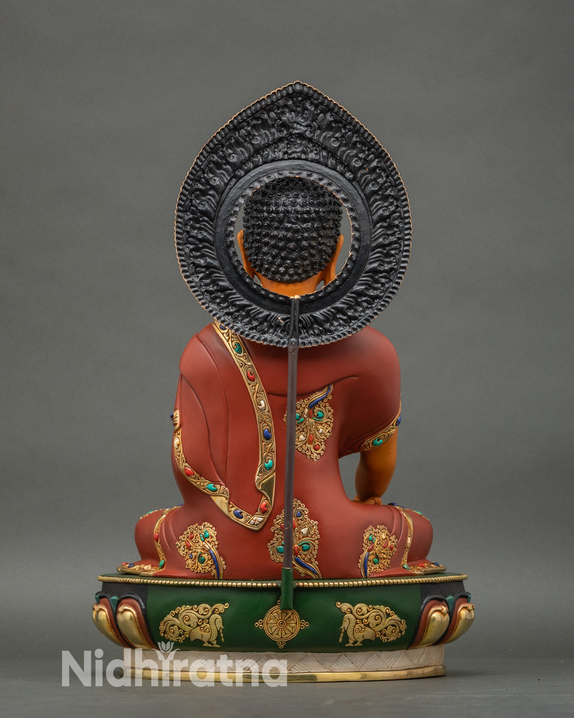 Back view of Shakyamuni Buddha statue showing detailed copper carvings and lotus flower pedestal