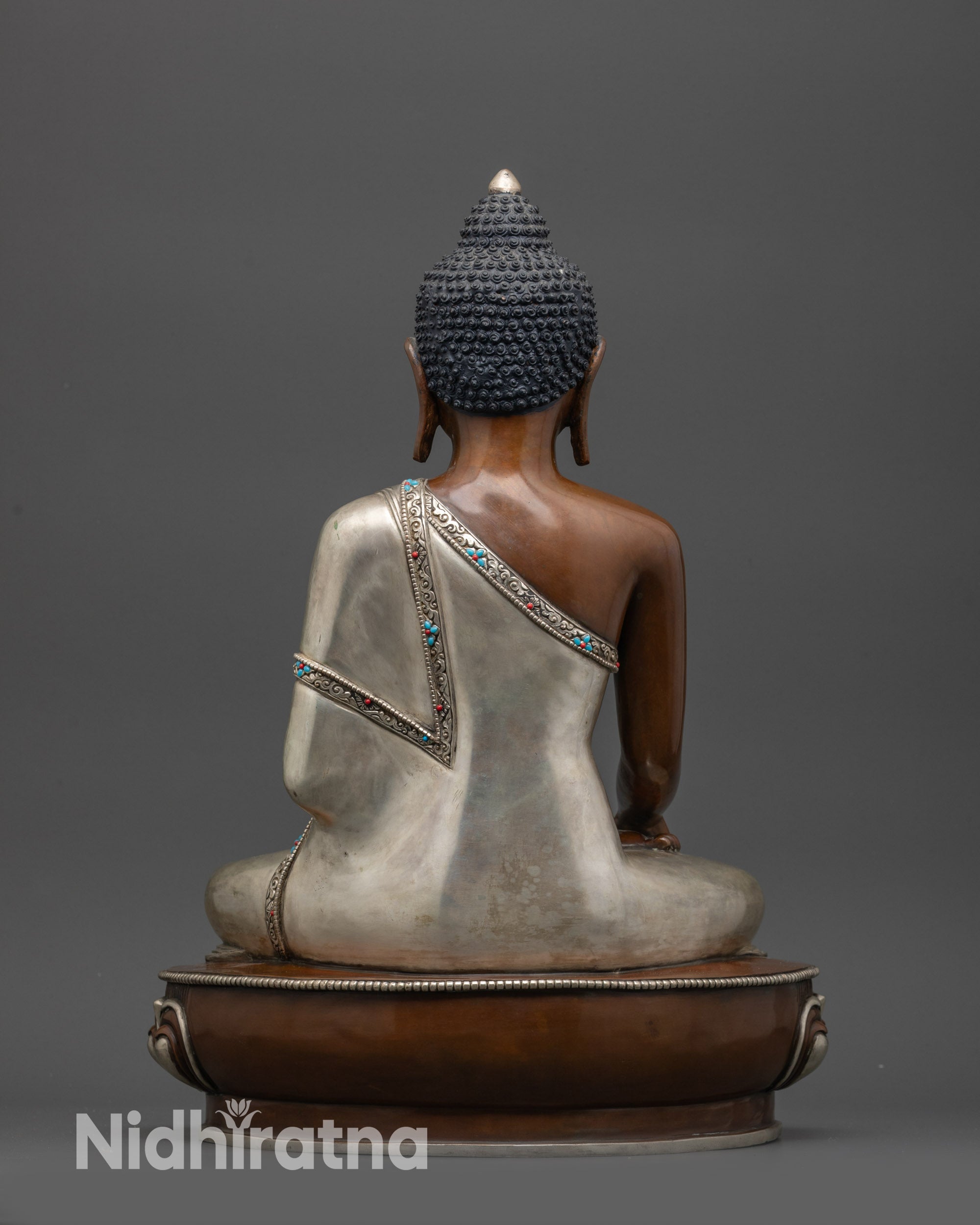 Back view of Shakyamuni Buddha statue with brownish hue and semi-precious stone details