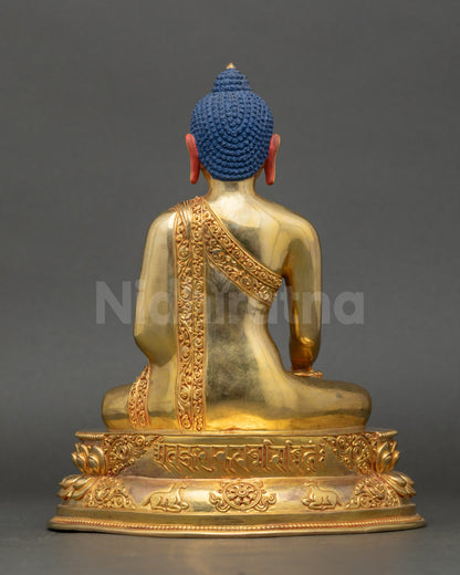 Back view of Shakyamuni Buddha statue showing detailed robe carvings and lotus base