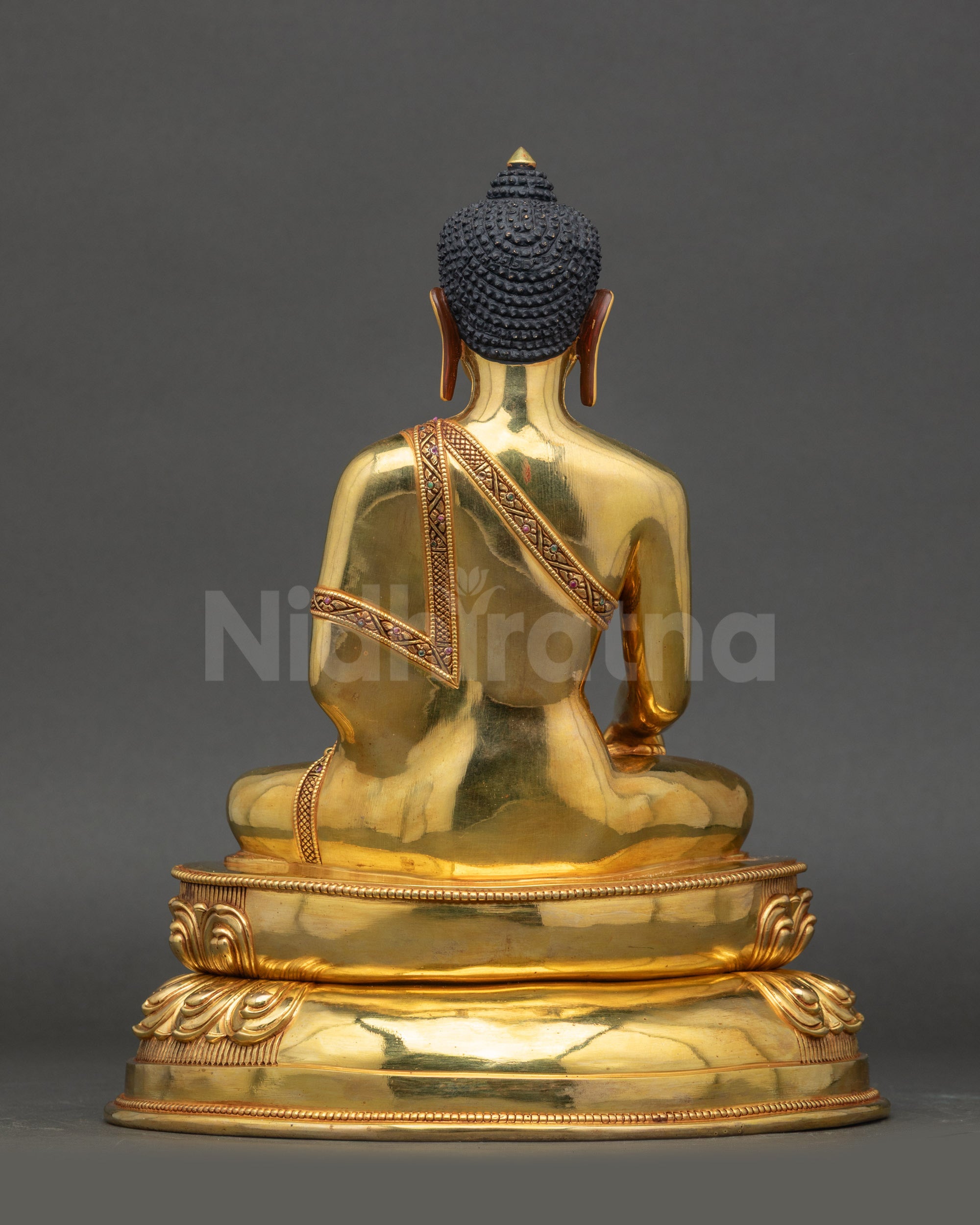 Back view of Siddhartha Gautama Buddha statue showing polished gold and lotus base