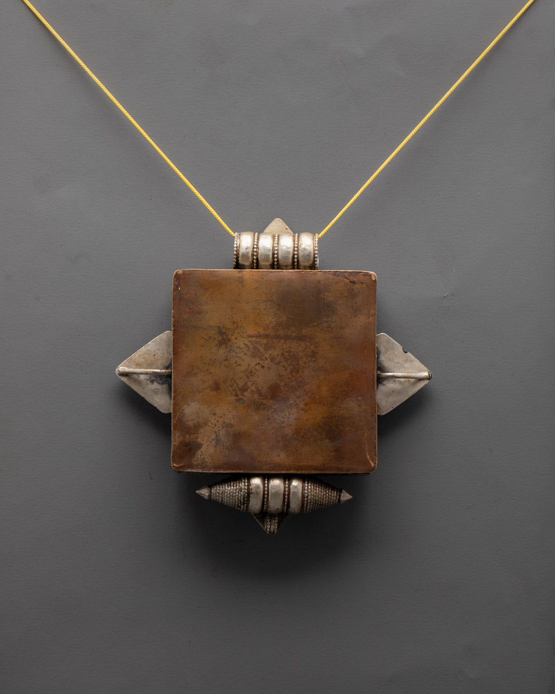 Back view of Tibetan copper locket displaying traditional artisan patterns