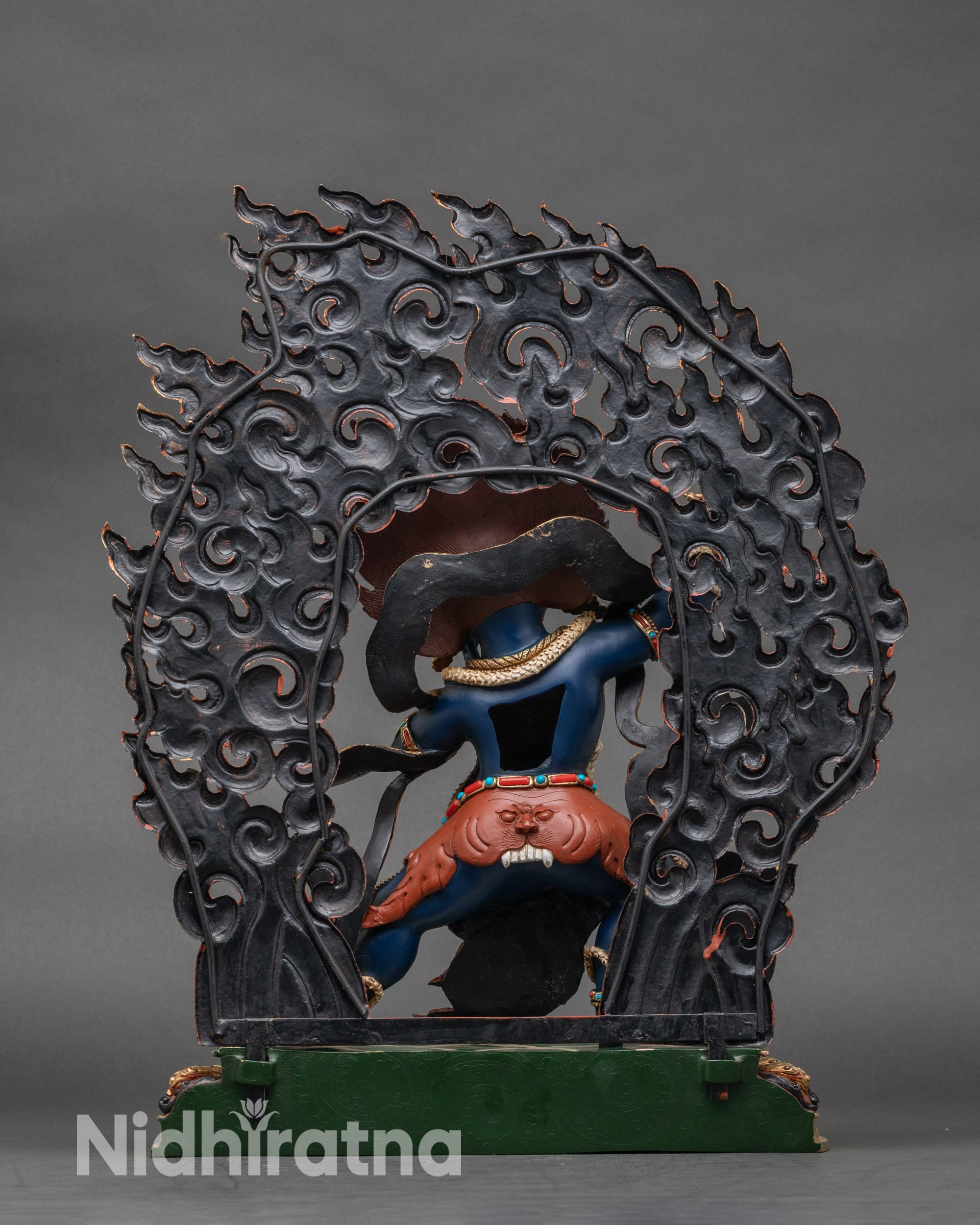 Back view of Vajrapani statue showing ornate lotus seat and decorative flames