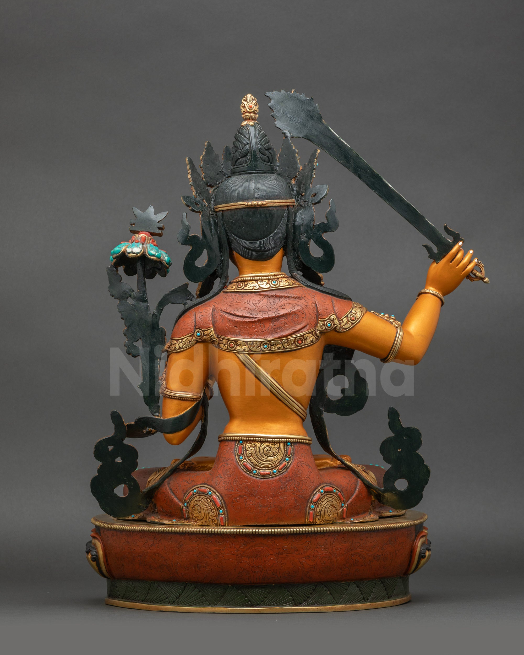 Back view of colourful Manjushri statue displaying intricate garments and gold accents