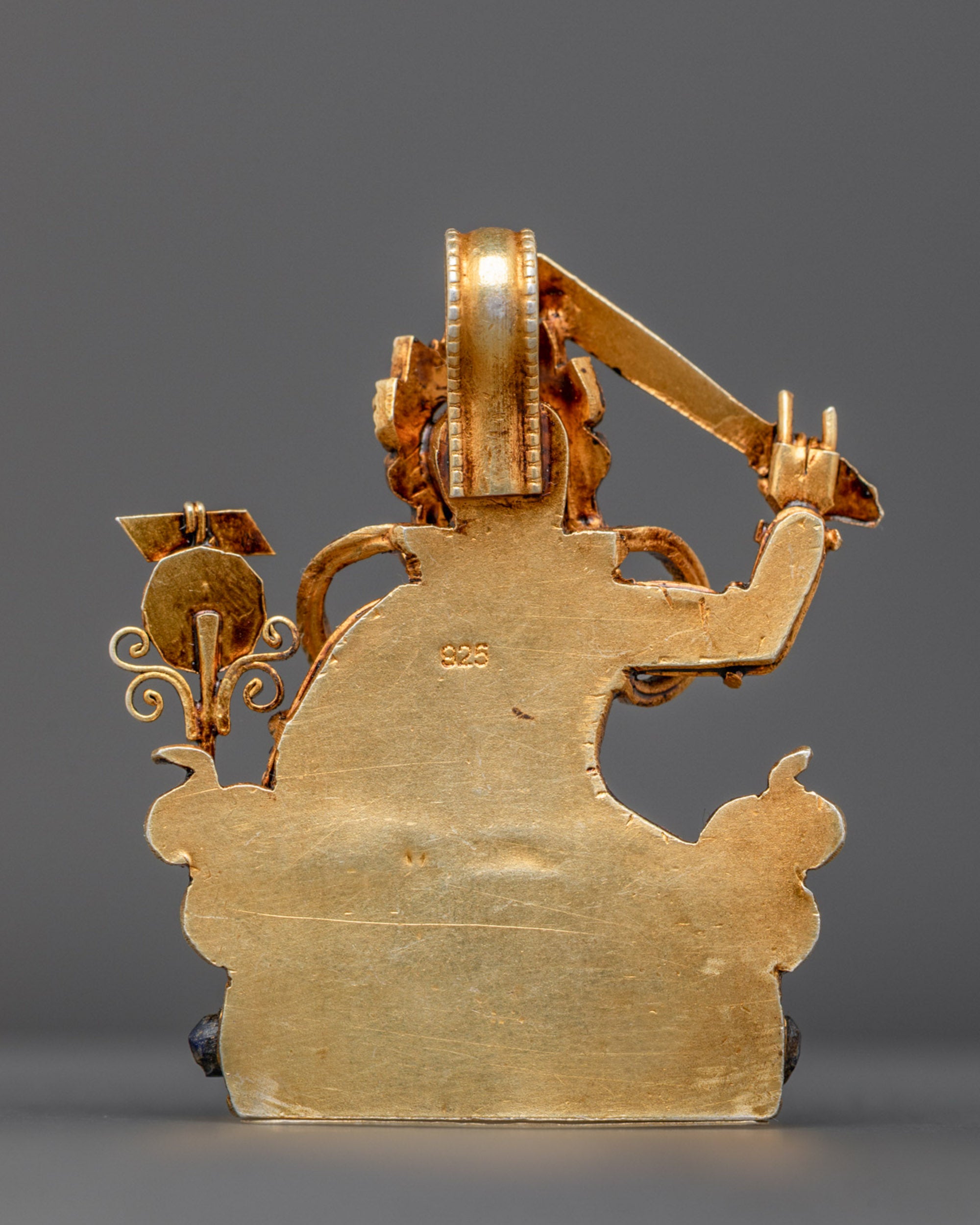 Back view of gold-gilded Manjushri amulet with traditional artisan filigree patterns