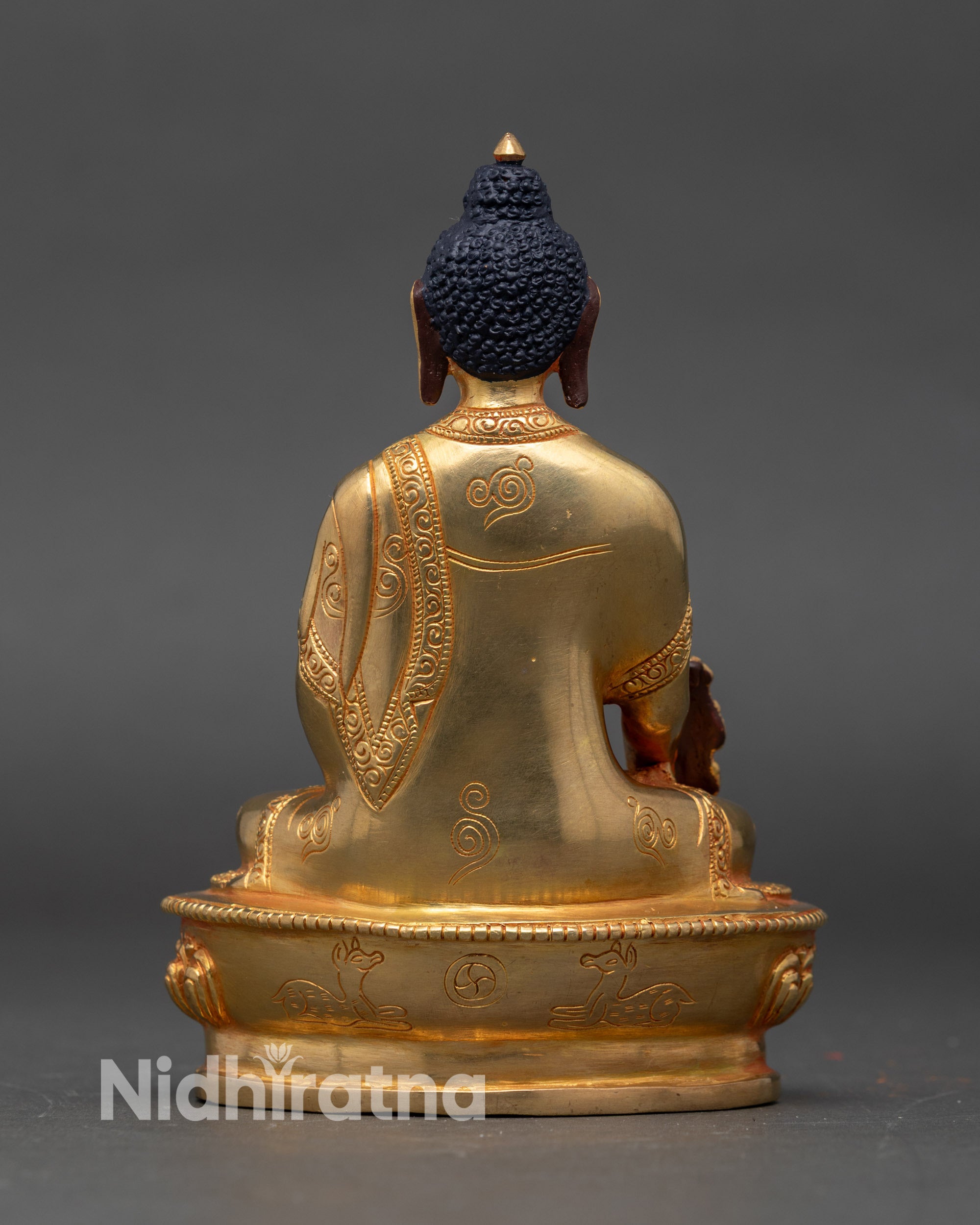 Back view of gold-gilded Medicine Buddha statue with lotus throne and traditional detailing