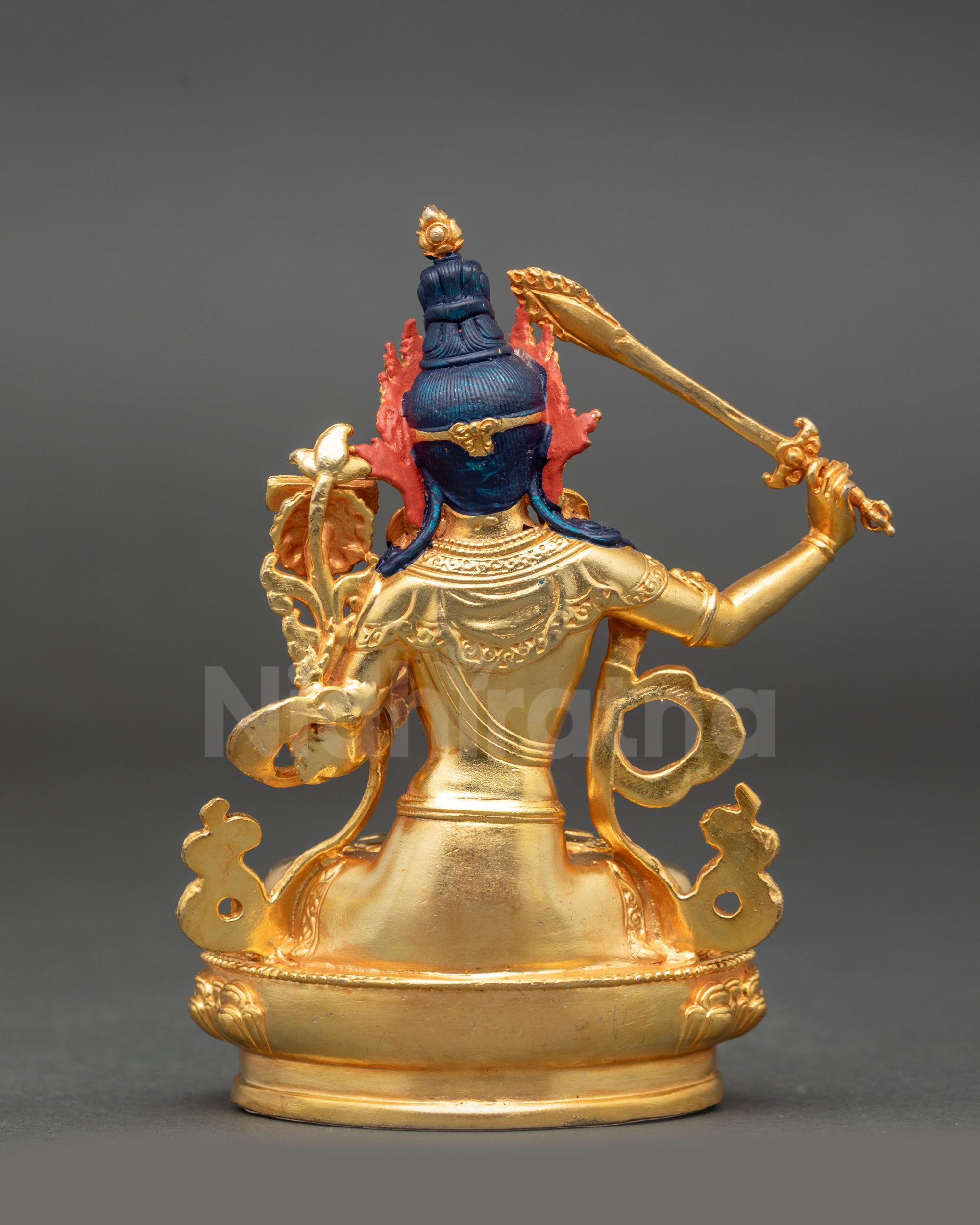 Back view of gold fire-gilded Manjushri seated on lotus with intricate detailing