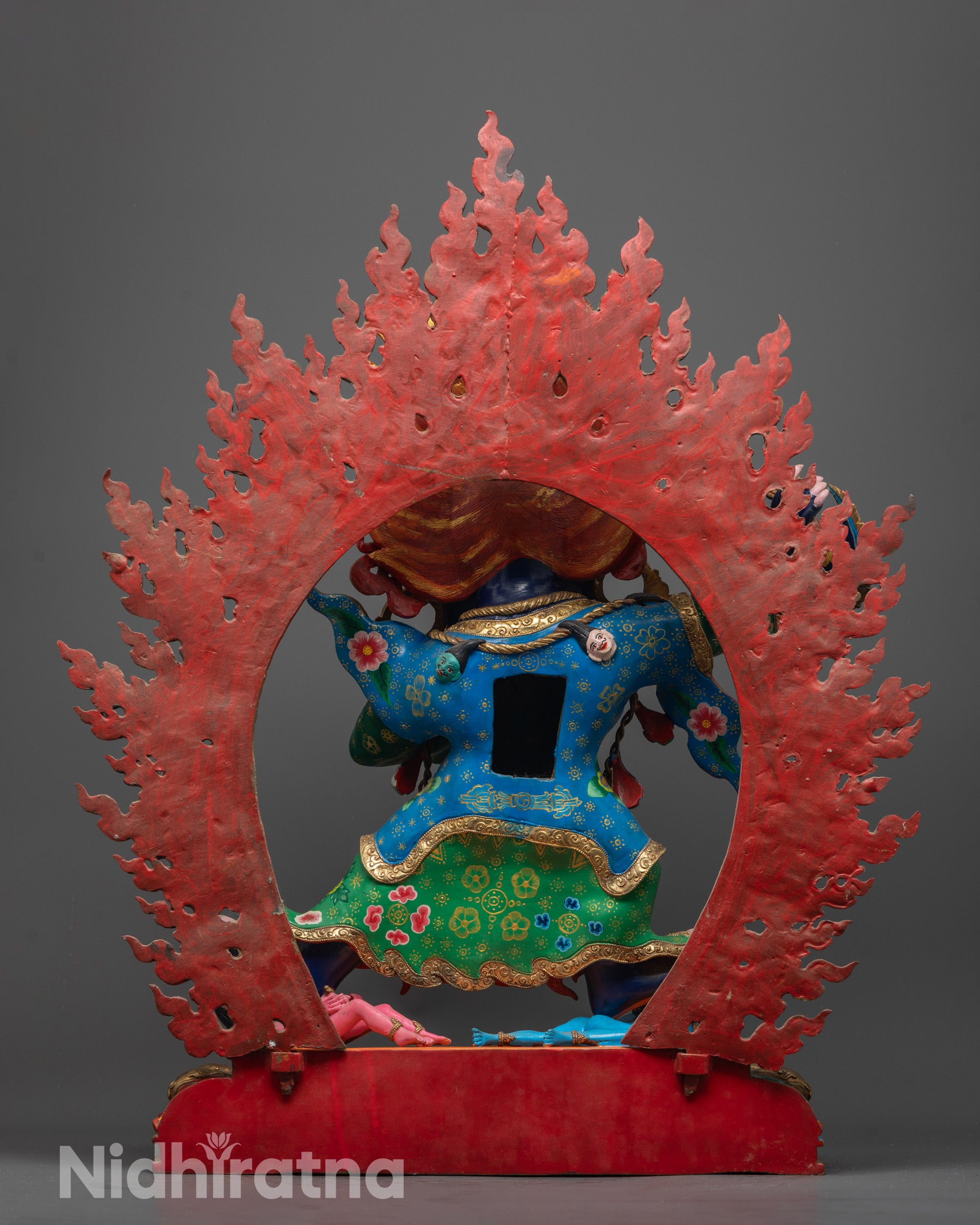 Back view of hand-carved Mahakala Bernagchen Statue showing subdued human figures