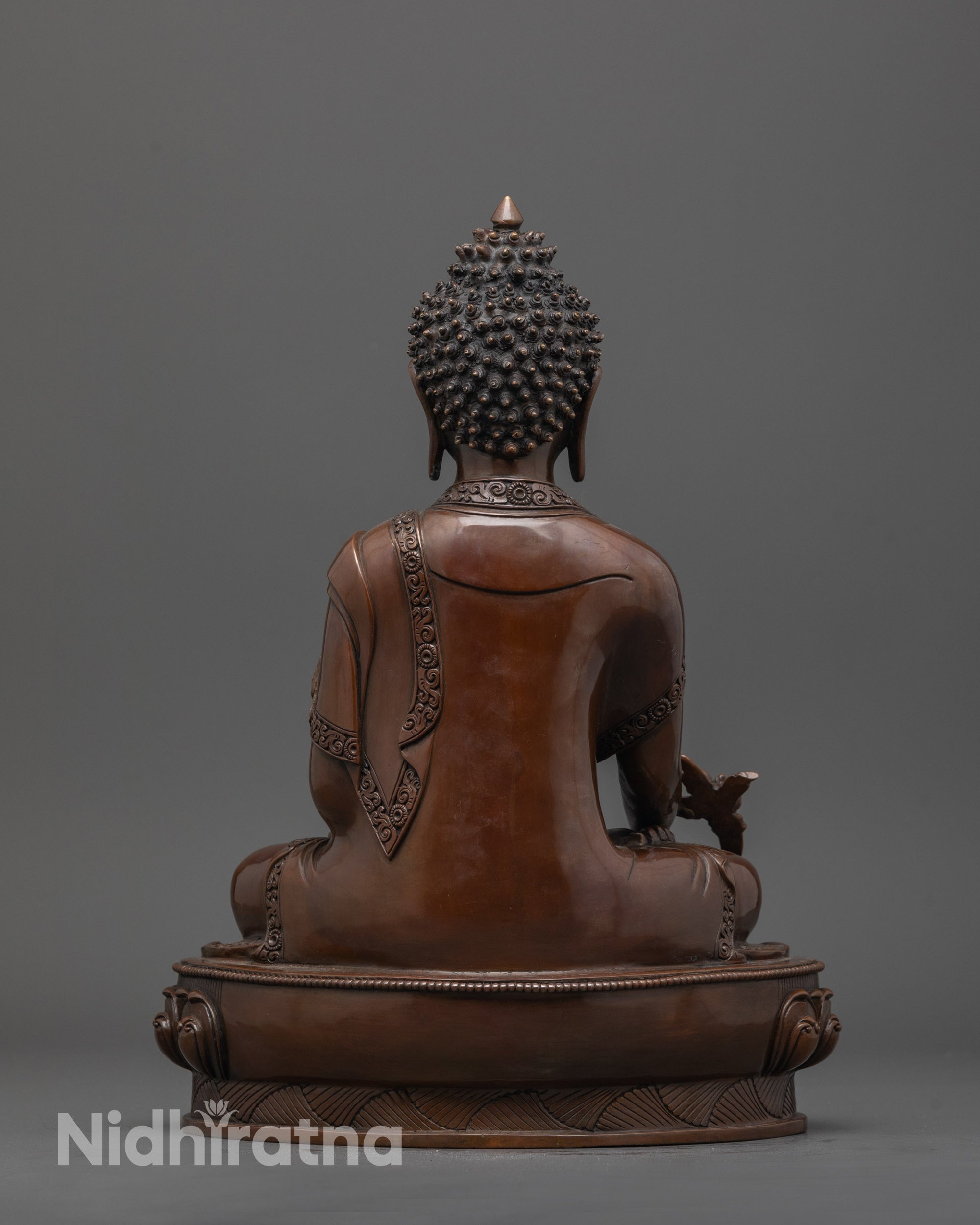 Back view of handcrafted Medicine Buddha statue showing oxidized texture and fine carving details