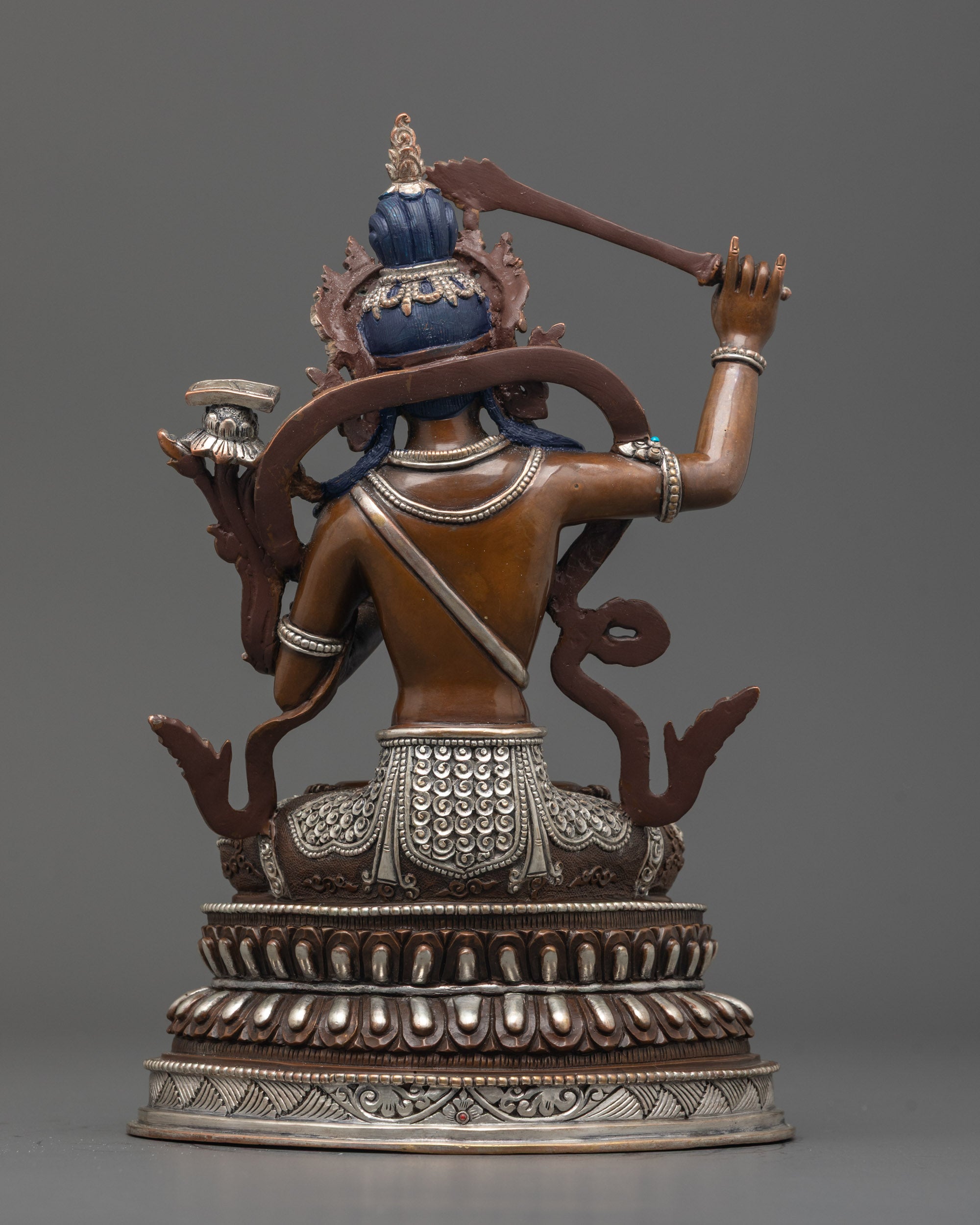 Back view of oxidized Manjushri statue seated on double-layered lotus base with details