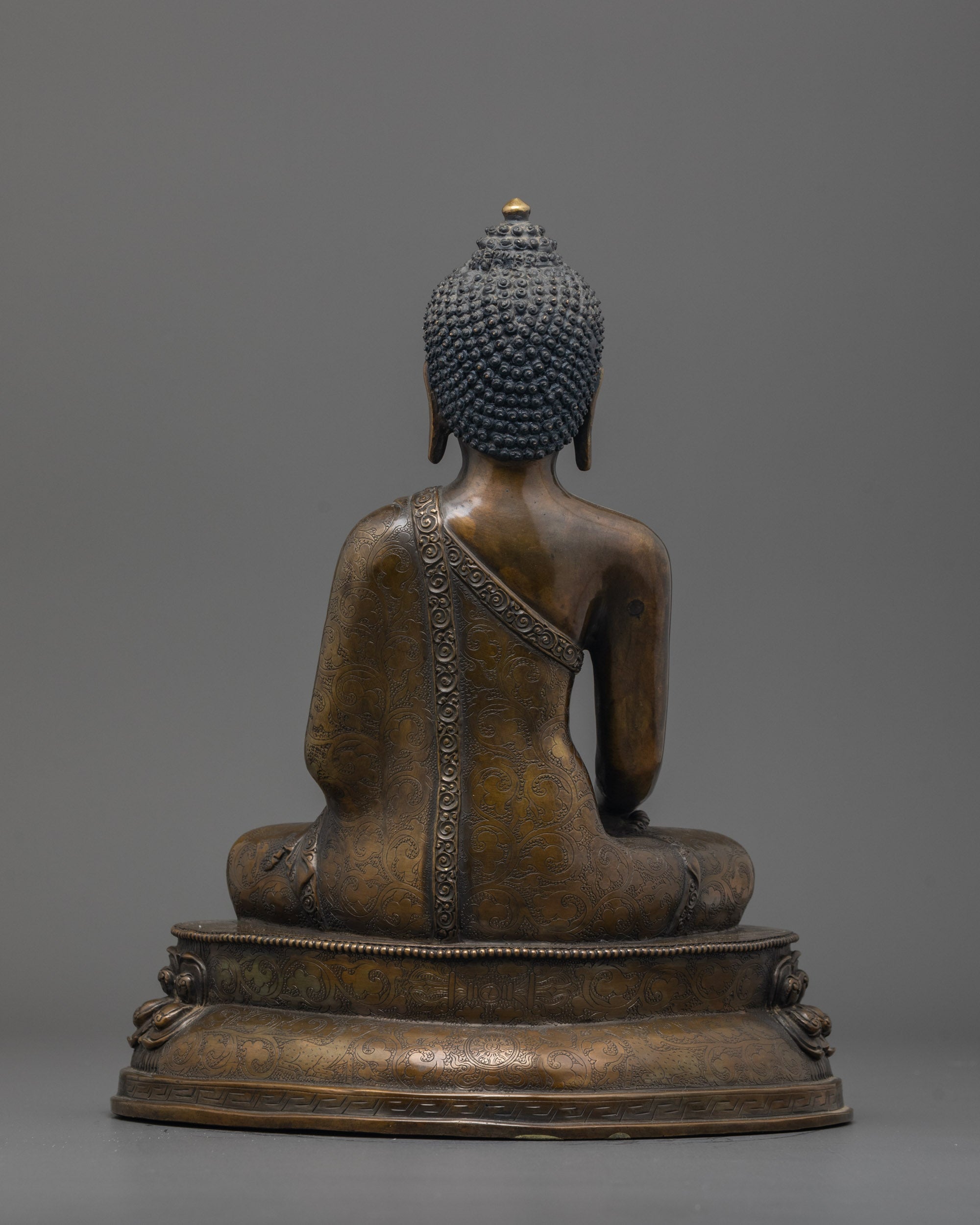 Back view of oxidized Shakyamuni Buddha statue highlighting detailed robe and lotus base