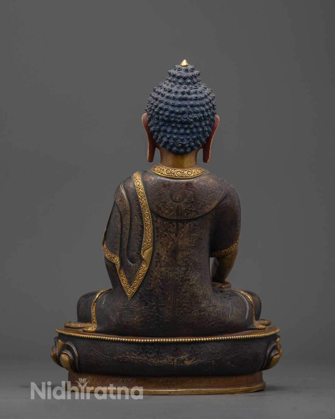 Back view of oxidized copper Shakyamuni Buddha statue with detailed robe and lotus base