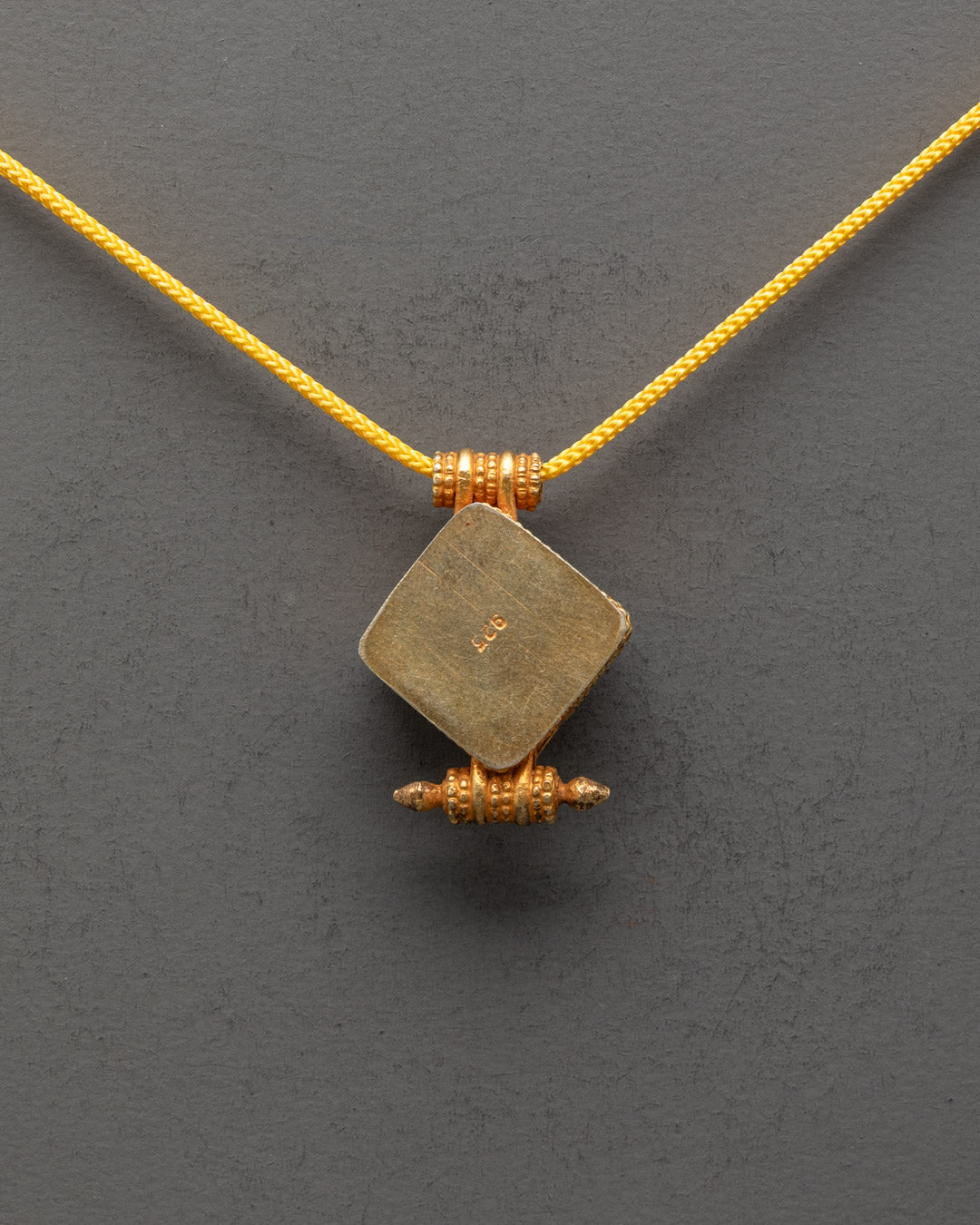 Back view of religious Tibetan pendant featuring traditional Buddhist symbols and ornate design



