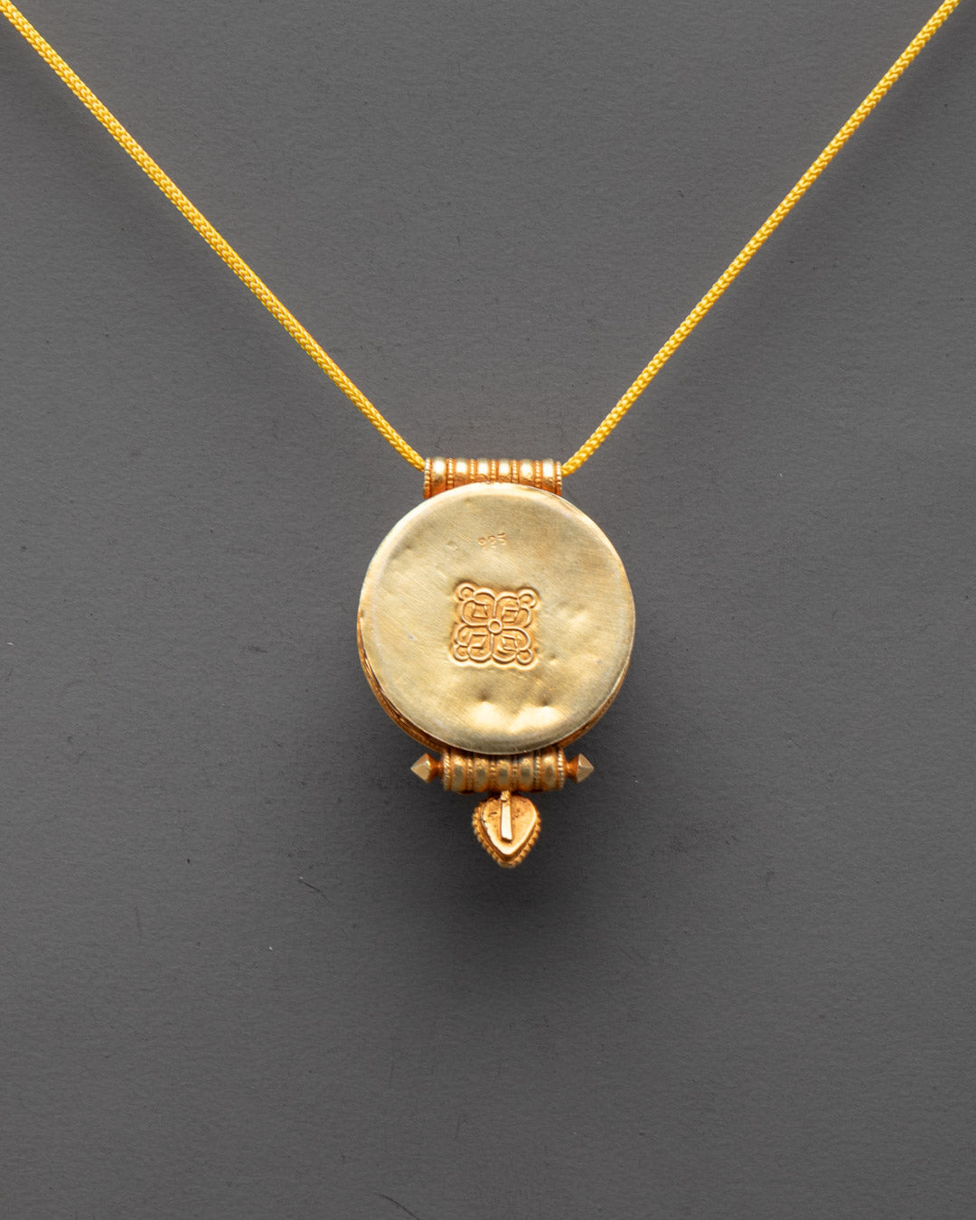 Back view of sacred Buddhist locket showcasing detailed craftsmanship and gold plating


