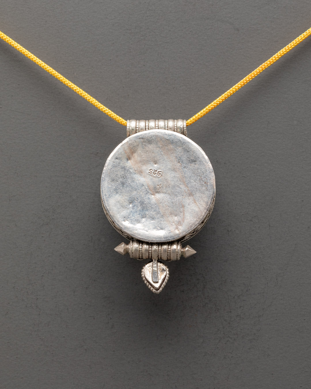 Back view of silver Tibetan pendant featuring traditional Buddhist symbols and design


