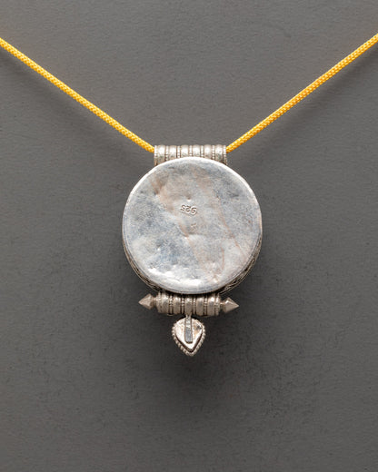 Back view of silver Tibetan pendant featuring traditional Buddhist symbols and design



