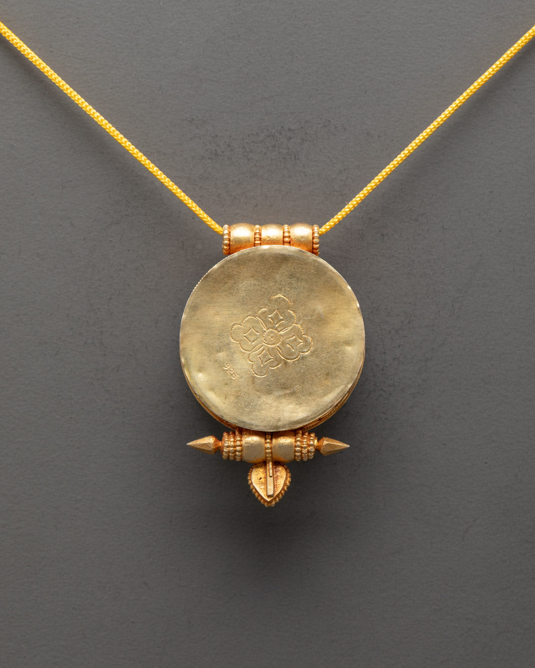 Back view of traditional Tibetan locket handcrafted in Patan with ornate sacred patterns