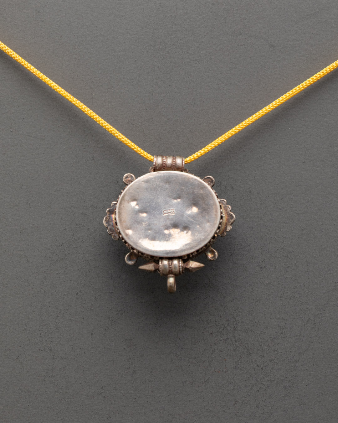Back view of vintage Tibetan amulet locket with intricate copper carvings and patterns