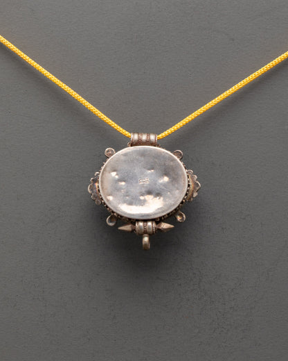 Back view of vintage Tibetan amulet locket with intricate copper carvings and patterns