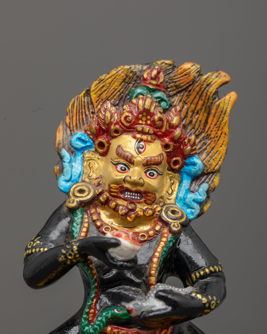 Black Dzambhala statue showing precise carvings on floating robe halo and jewelry