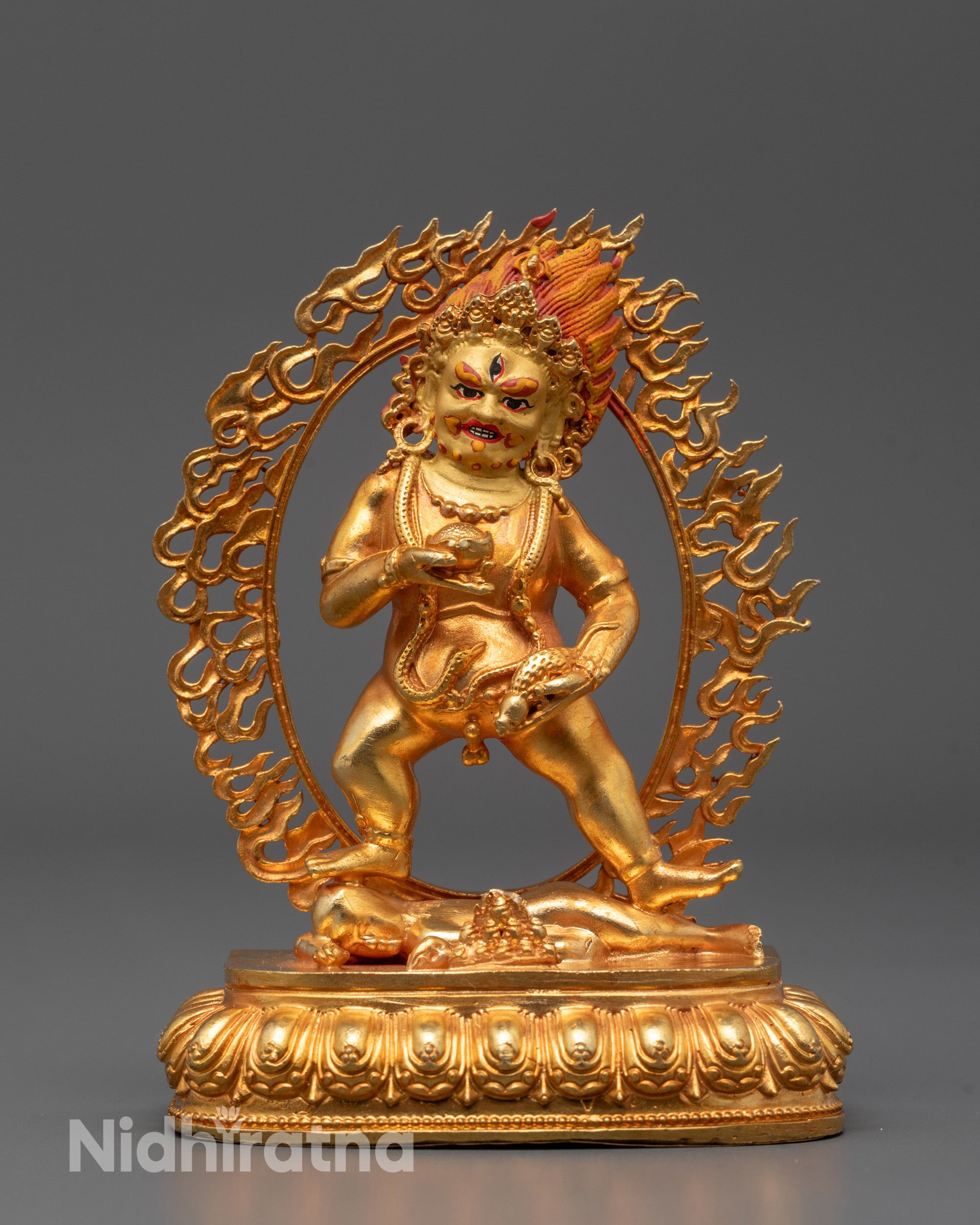 Black Dzambhala statue standing on lotus base holding fruit and mongoose with golden halo