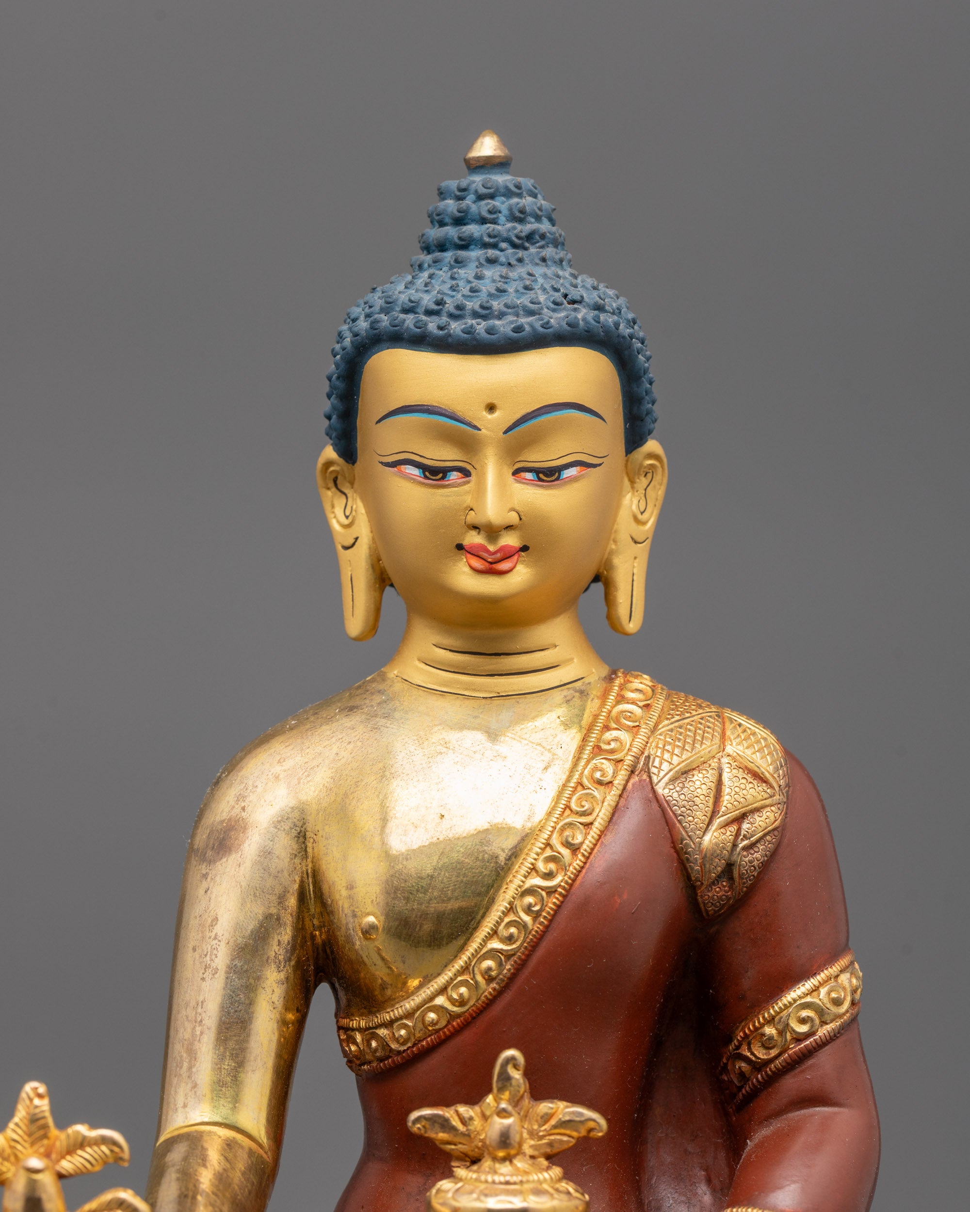 close up of Medicine Buddha face and myrobalan bowl showing lost wax details and gold gilding